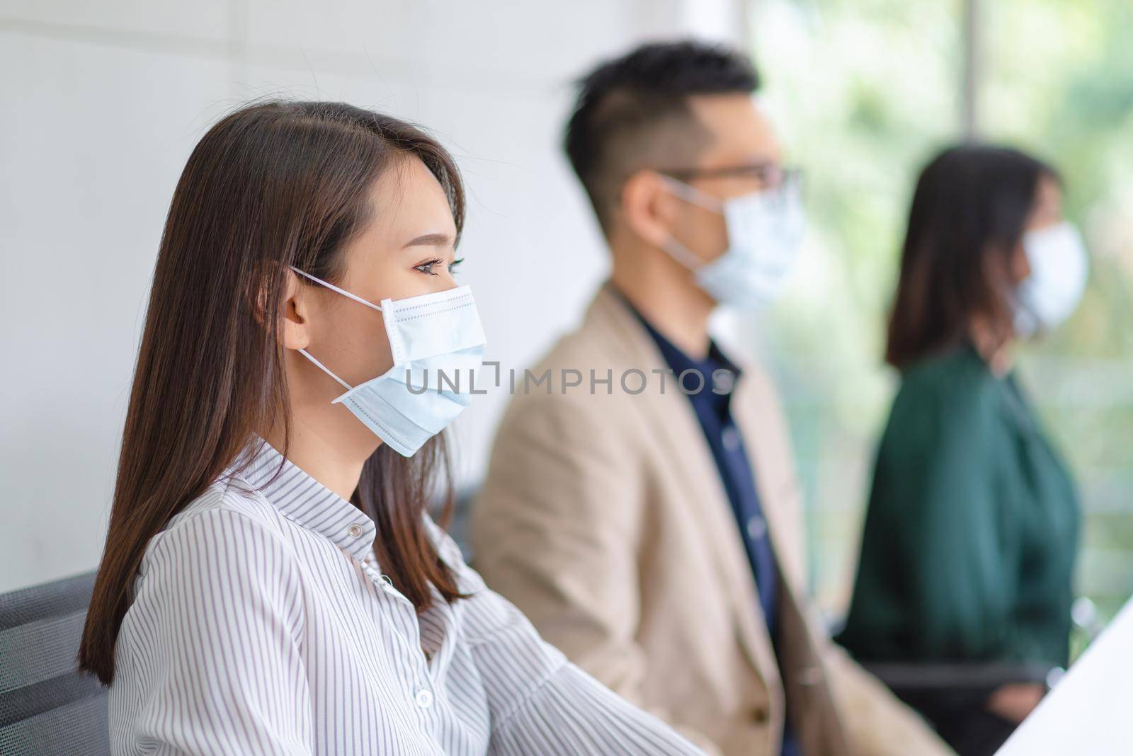 Business employees wearing mask during work in office to keep hygiene follow company policy by Nuamfolio