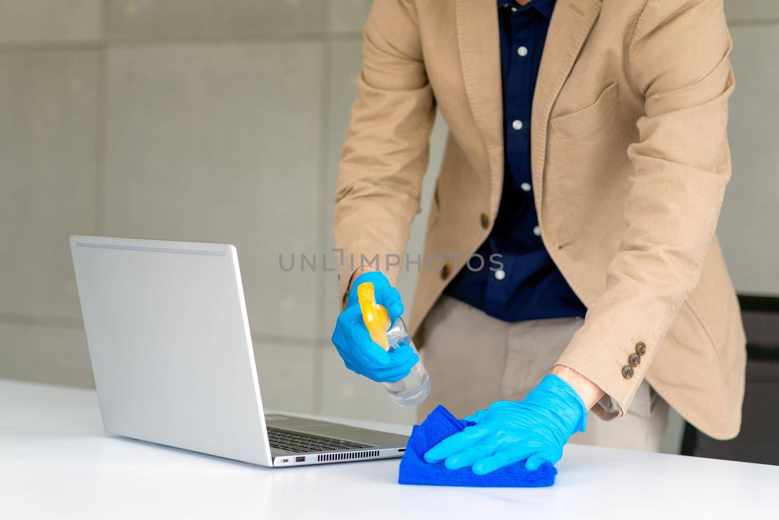 Business man wearing mask and using personal sanitizer to cleaning his office to keep hygiene by Nuamfolio