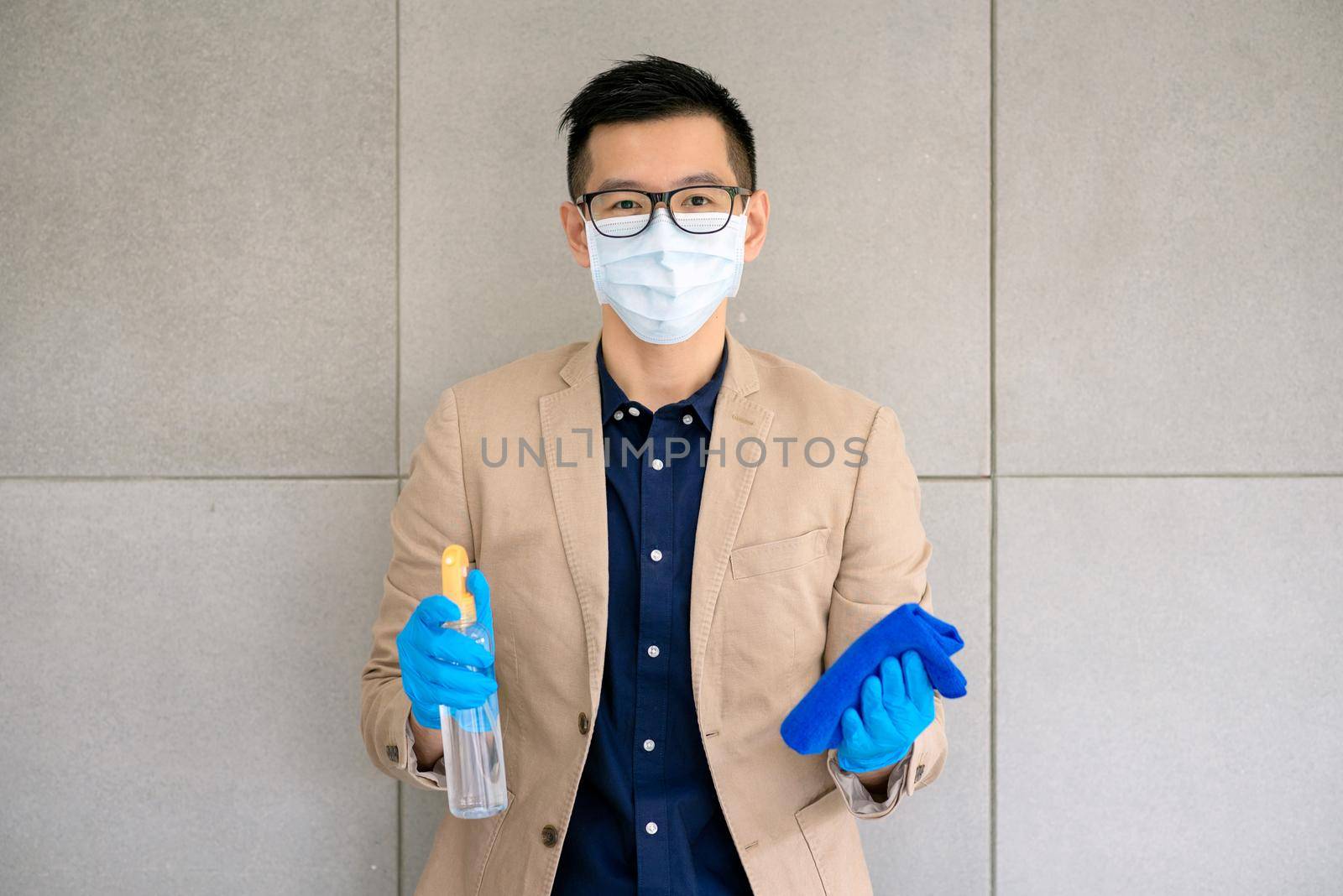 Business man wearing mask and using personal sanitizer to cleaning his office to keep hygiene.Preventive during the period of epidemic from coronavirus or covid19.