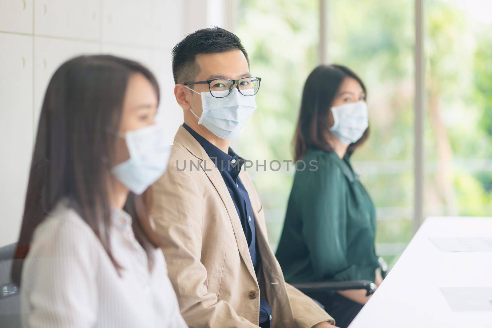 Business employees wearing mask during work in office to keep hygiene follow company policy by Nuamfolio