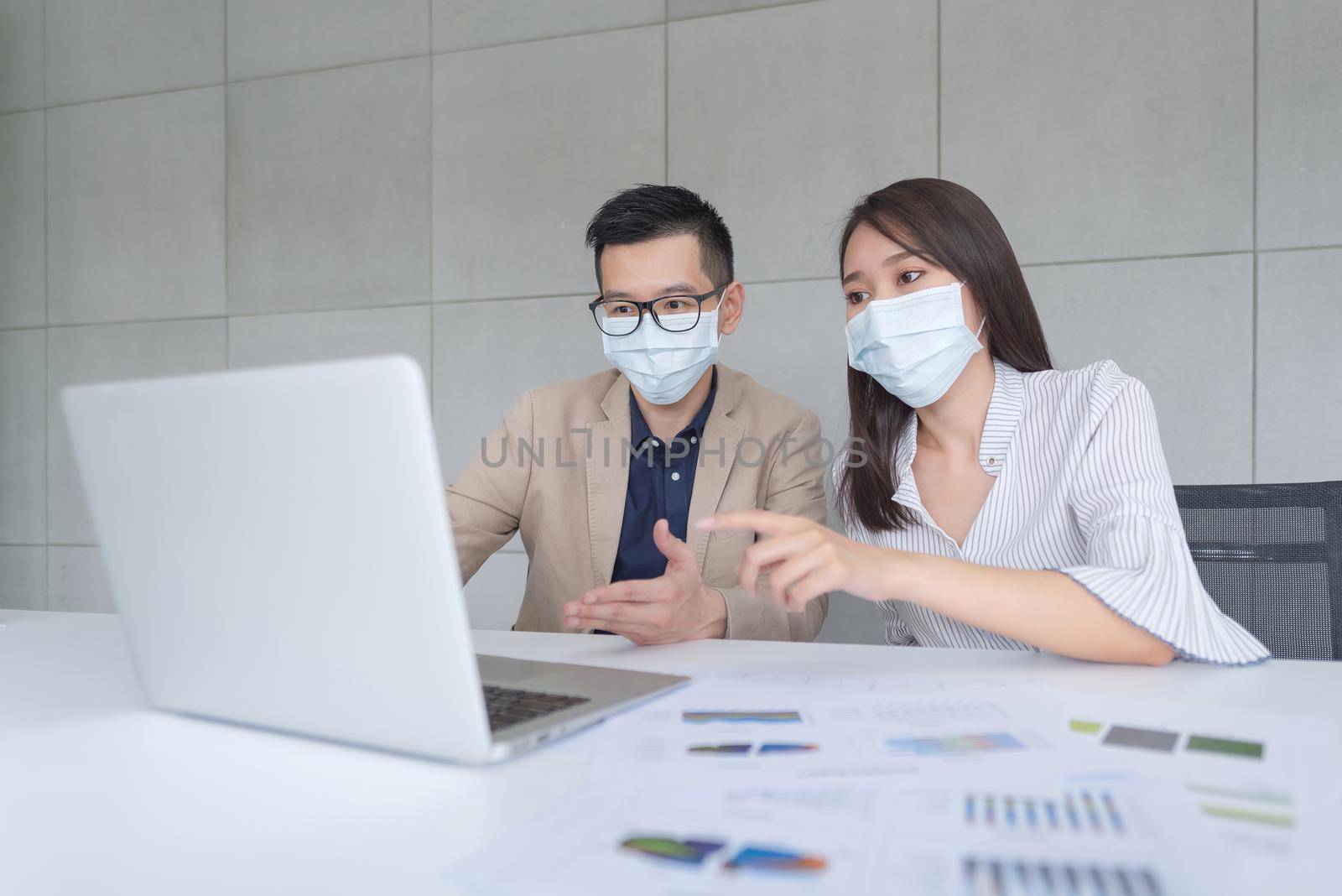 Business employees wearing mask during work in office to keep hygiene follow company policy by Nuamfolio