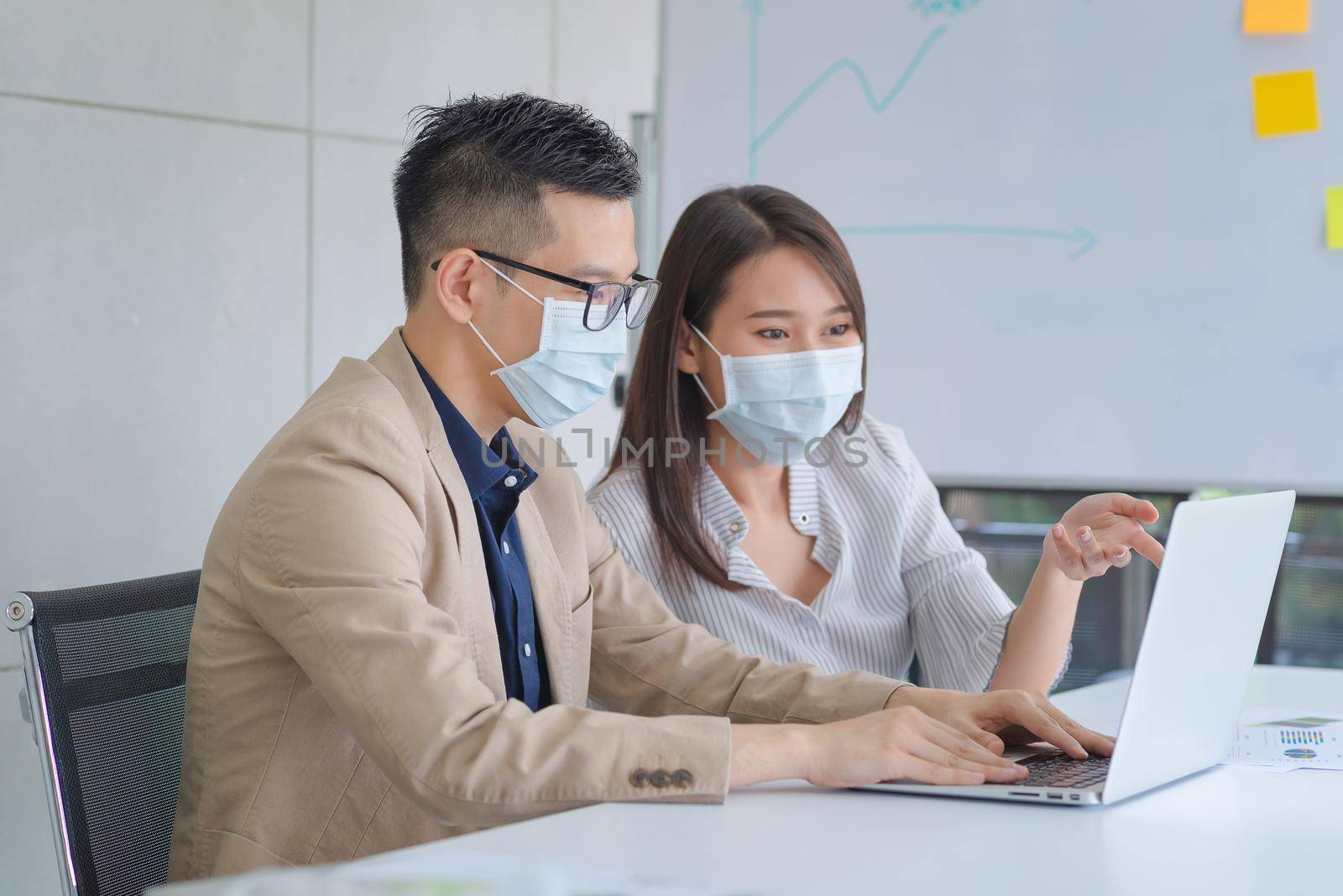 Business employees wearing mask during work in office to keep hygiene follow company policy. by Nuamfolio