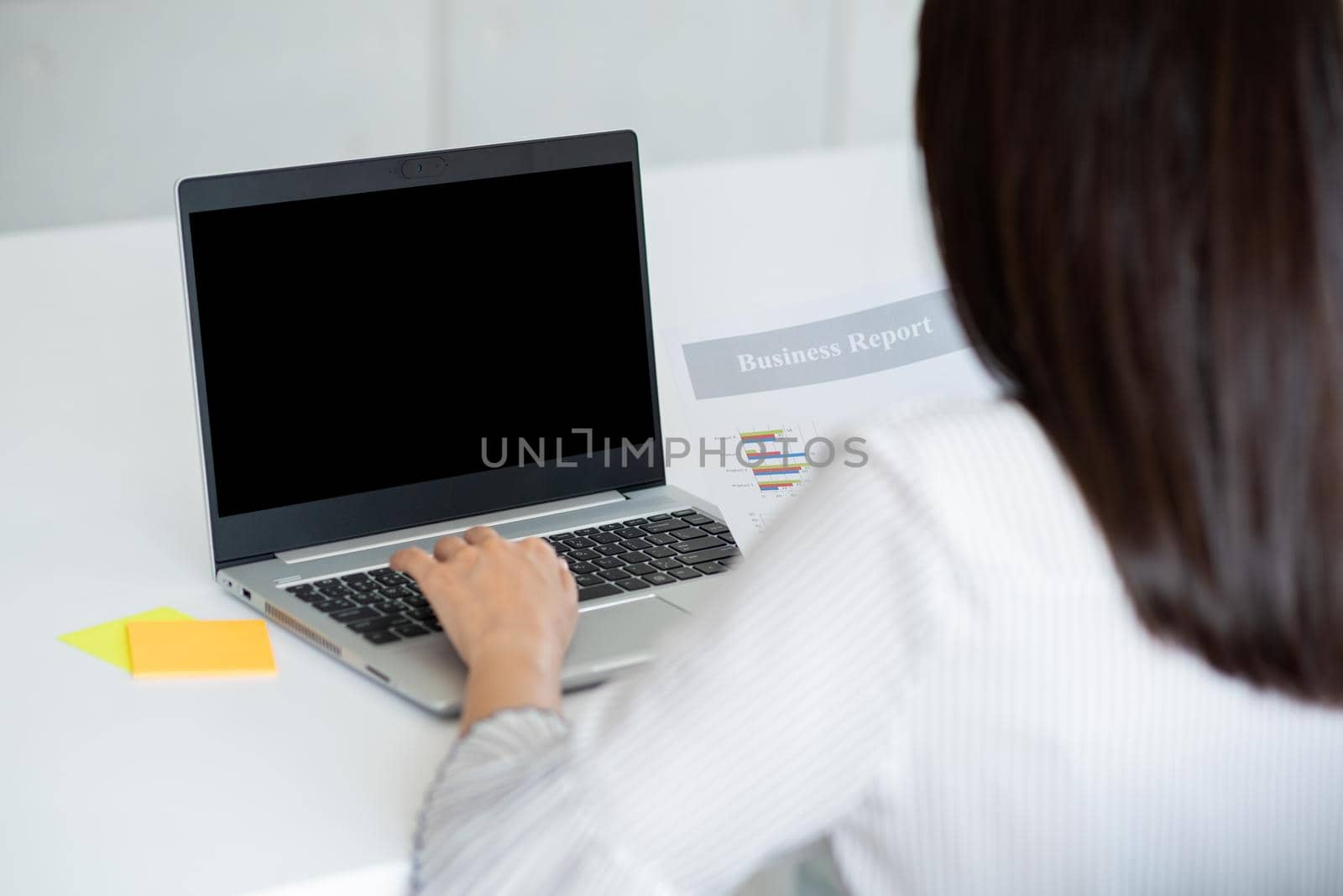 Back view of Business woman using laptop with black screen in office. Photo design with copy space for mock up for business concept
