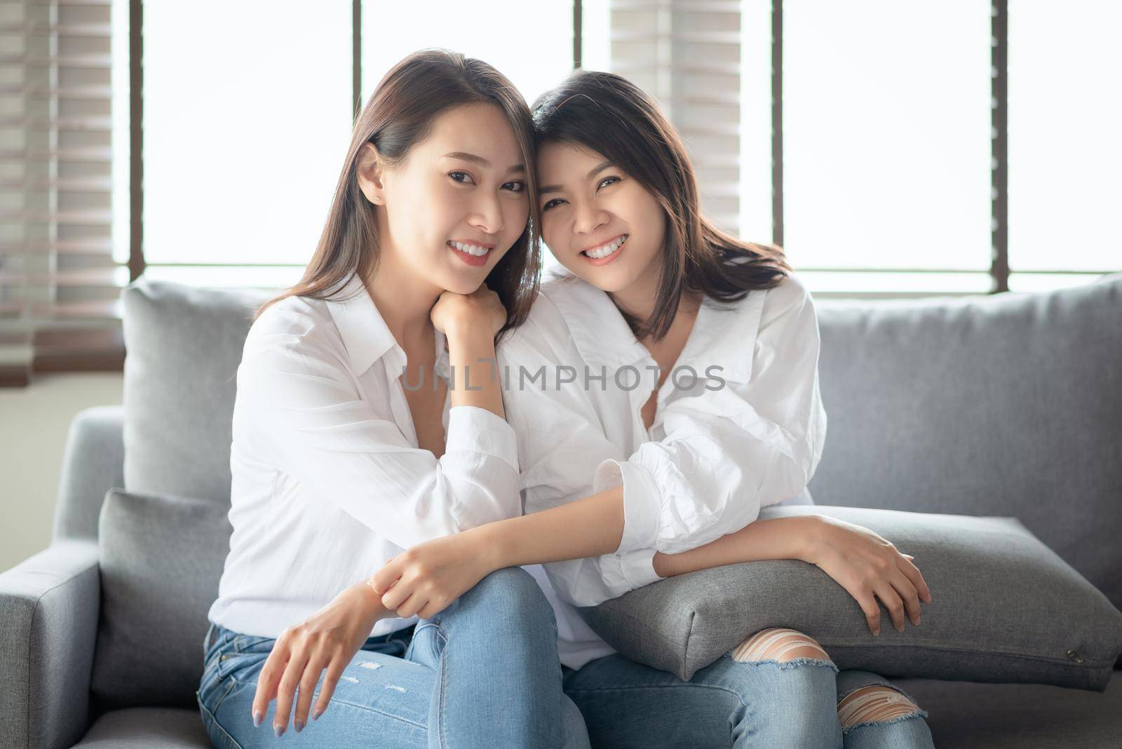 Two asian females take a portrait photo with charming smile in living room at home