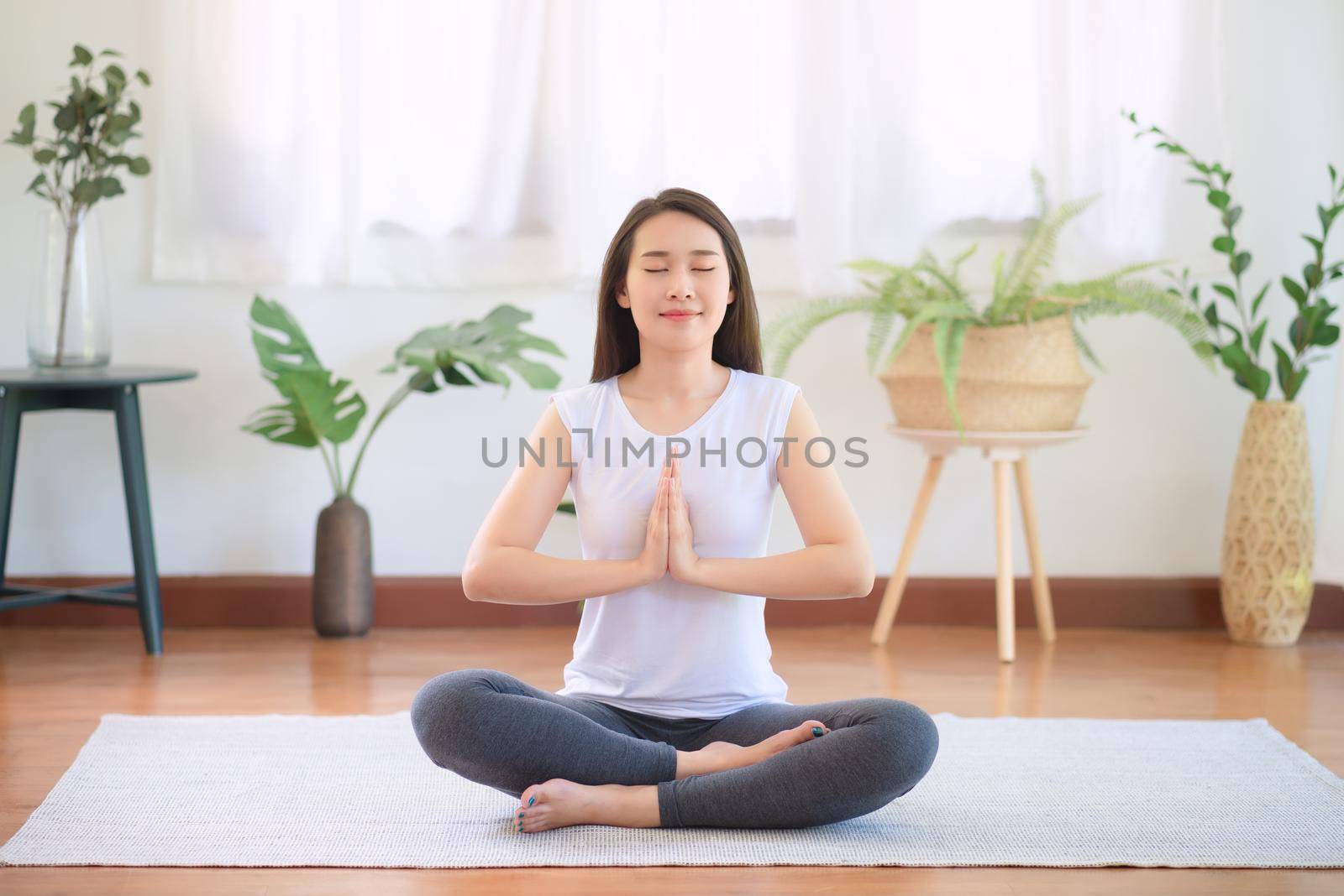 Beautiful asian woman keep calm and meditates while practicing yoga at home for healthy trend lifestyle by Nuamfolio