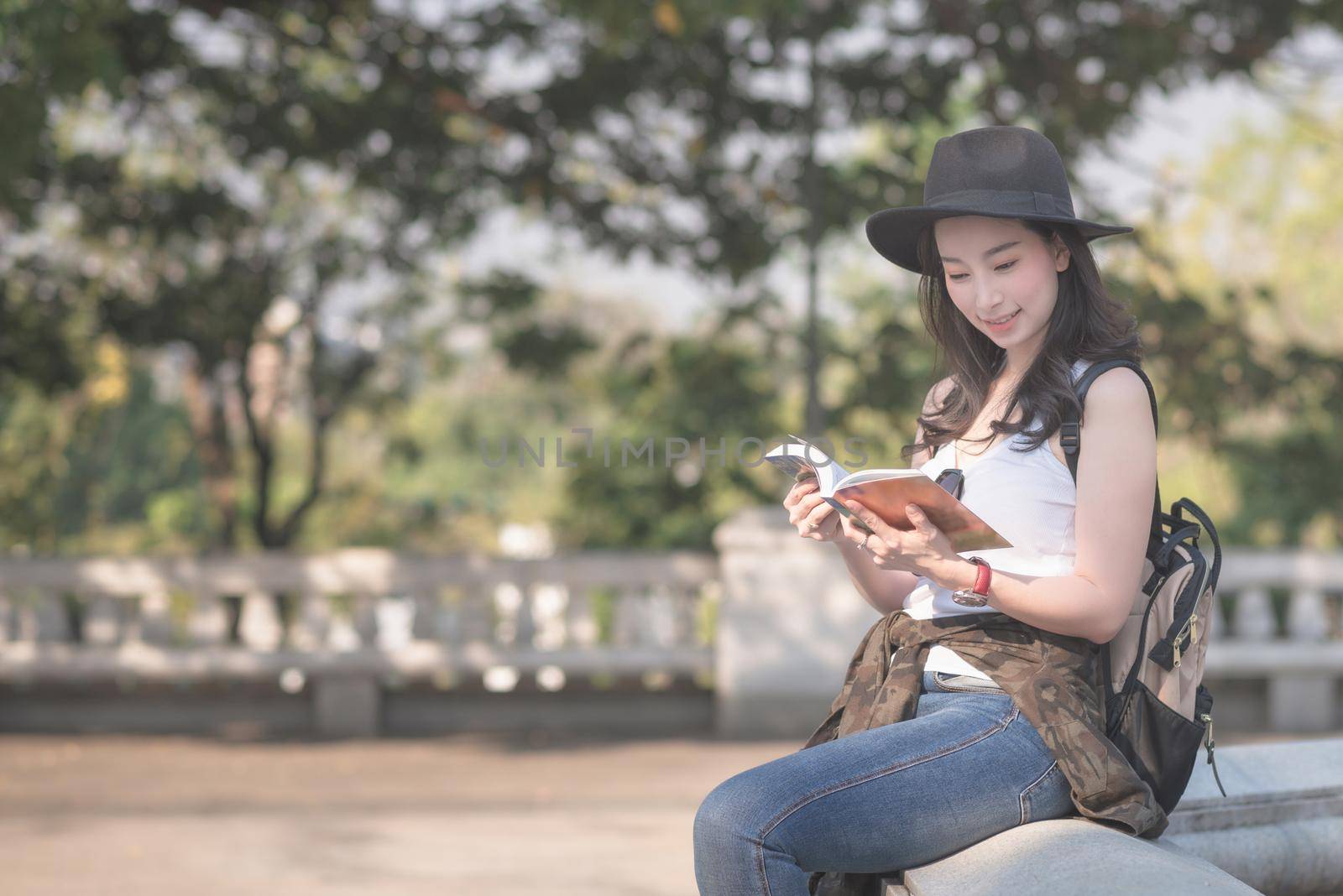 Beautiful asian solo tourist woman  reading the travel guide book searching for for tourists sightseeing spot. by Nuamfolio