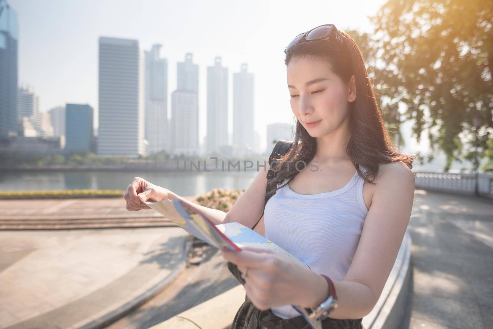 Beautiful asian solo tourist woman  looking at the map searching for tourists sightseeing spot. Vacation travel in summer.