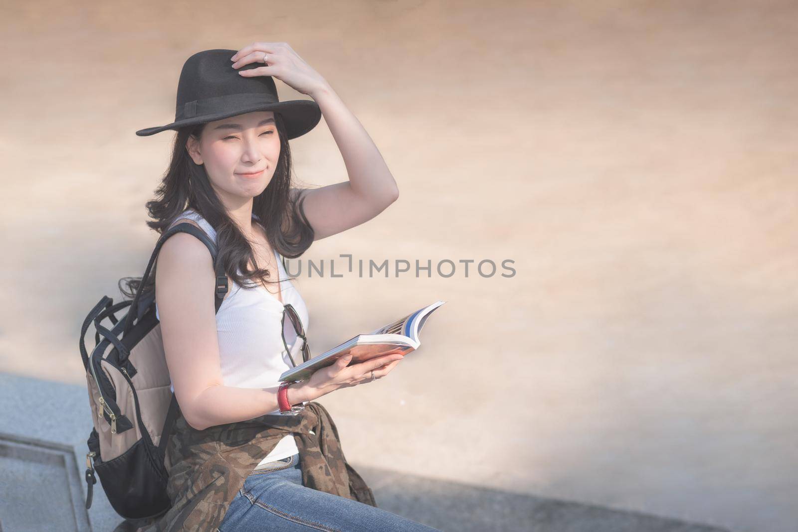 Beautiful asian solo tourist woman  reading the travel guide book searching for for tourists sightseeing spot by Nuamfolio