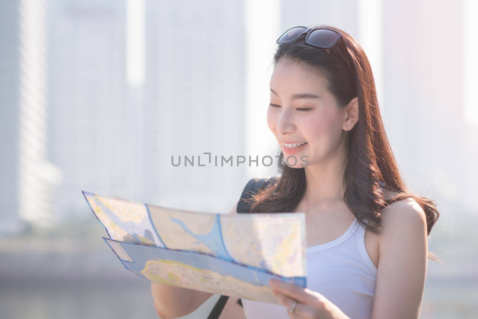 Beautiful asian solo tourist woman looking at the map searching for tourists sightseeing spot. Vacation travel in summer.