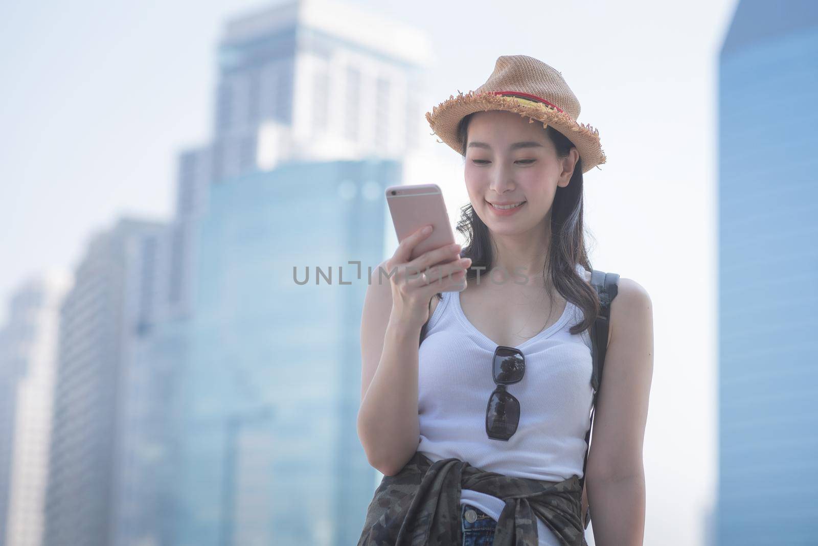 Beautiful asian solo tourist woman smiling and looking at mobile phone for searching tourists sightseeing spot by Nuamfolio