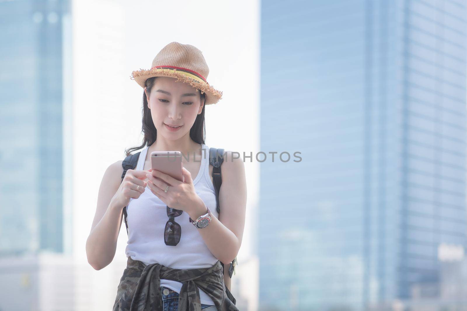 Beautiful asian solo tourist woman smiling and looking at mobile phone for searching tourists sightseeing spot. Vacation travel in summer