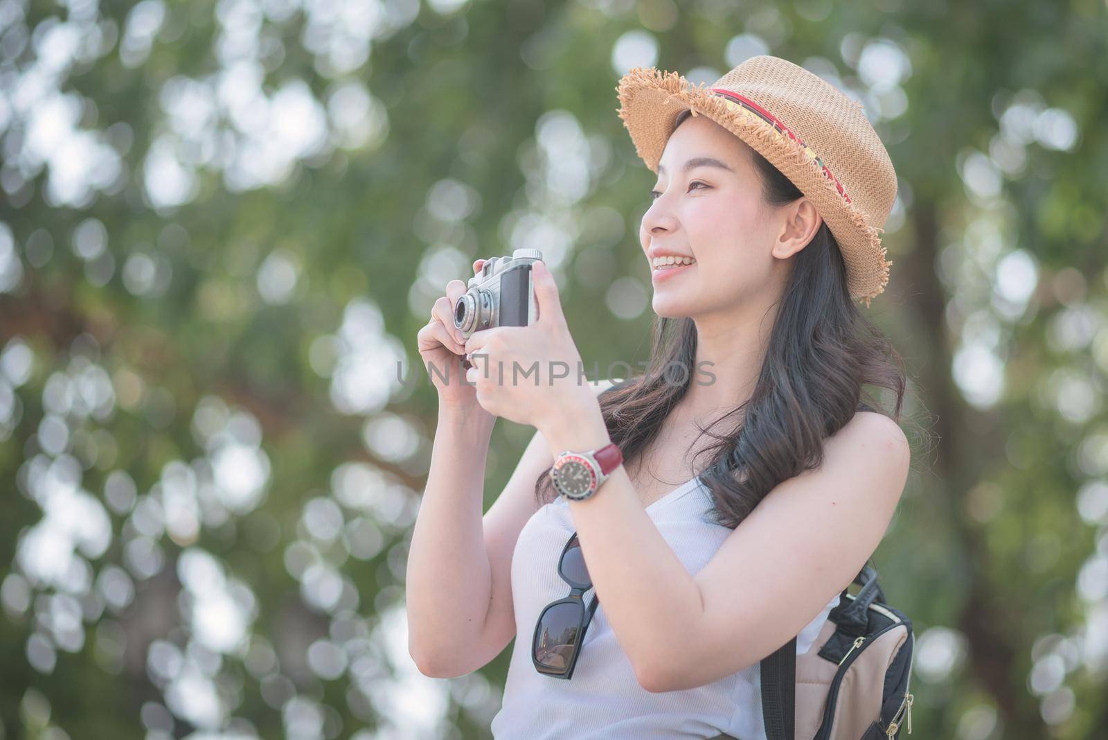 Beautiful asian solo tourist woman enjoy taking photo by retro camera at tourist sightseeing spot. Vacation travel in summer.