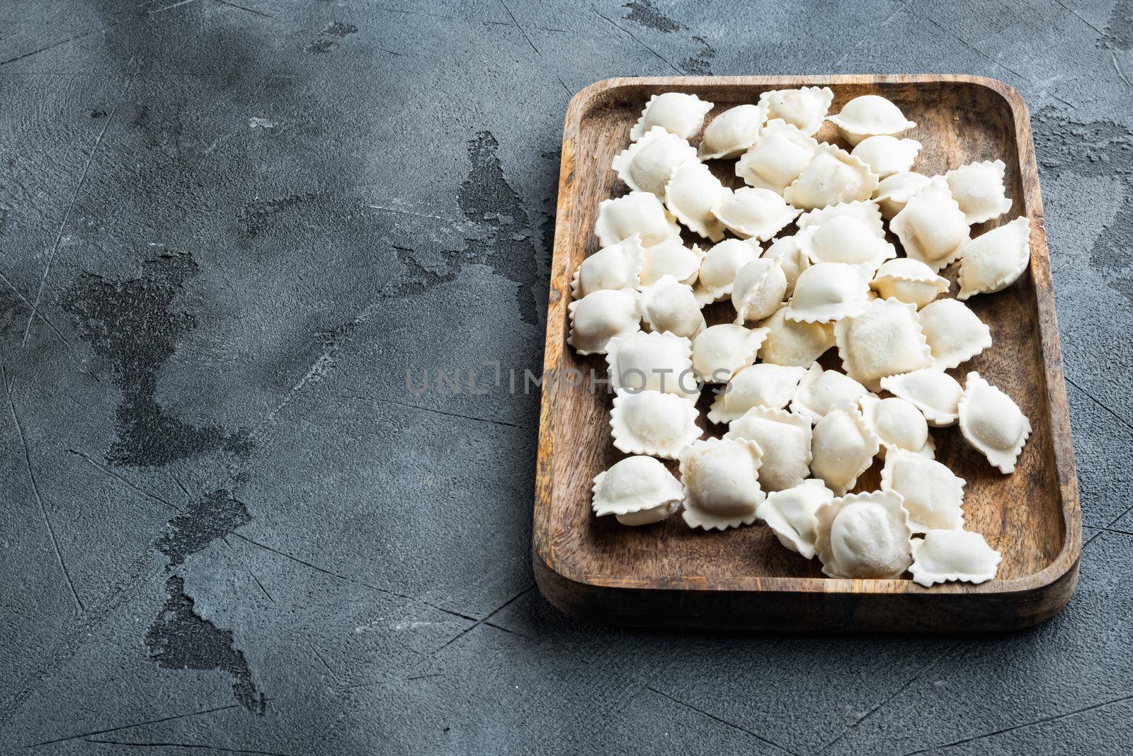 Frozen dumplings tortellini and ravioli set in wooden box, on gray background , with copyspace and space for text