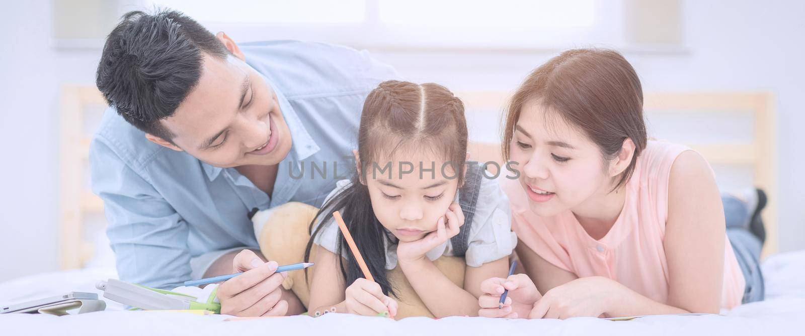 Asian family happy smiling and relax on bed at home. by Nuamfolio