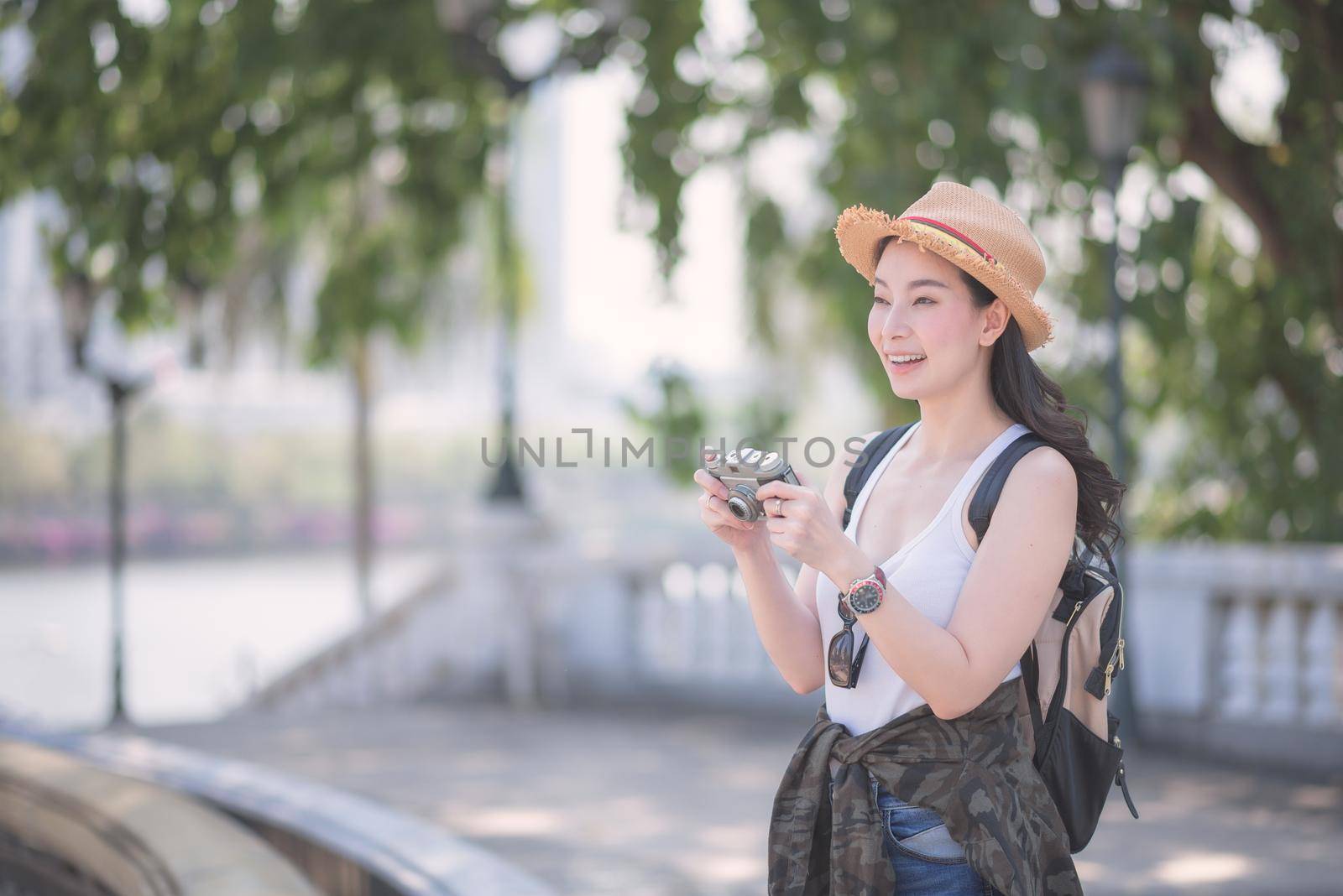 Beautiful asian solo tourist woman enjoy taking photo by retro camera at tourist sightseeing spot. Vacation travel in summer.