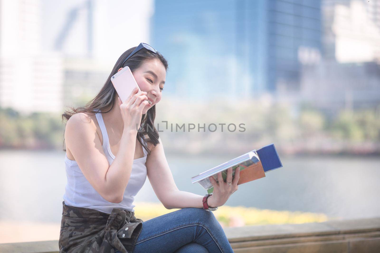 Beautiful asian tourist woman reading the travel guide book searching for for tourists sightseeing spot by Nuamfolio