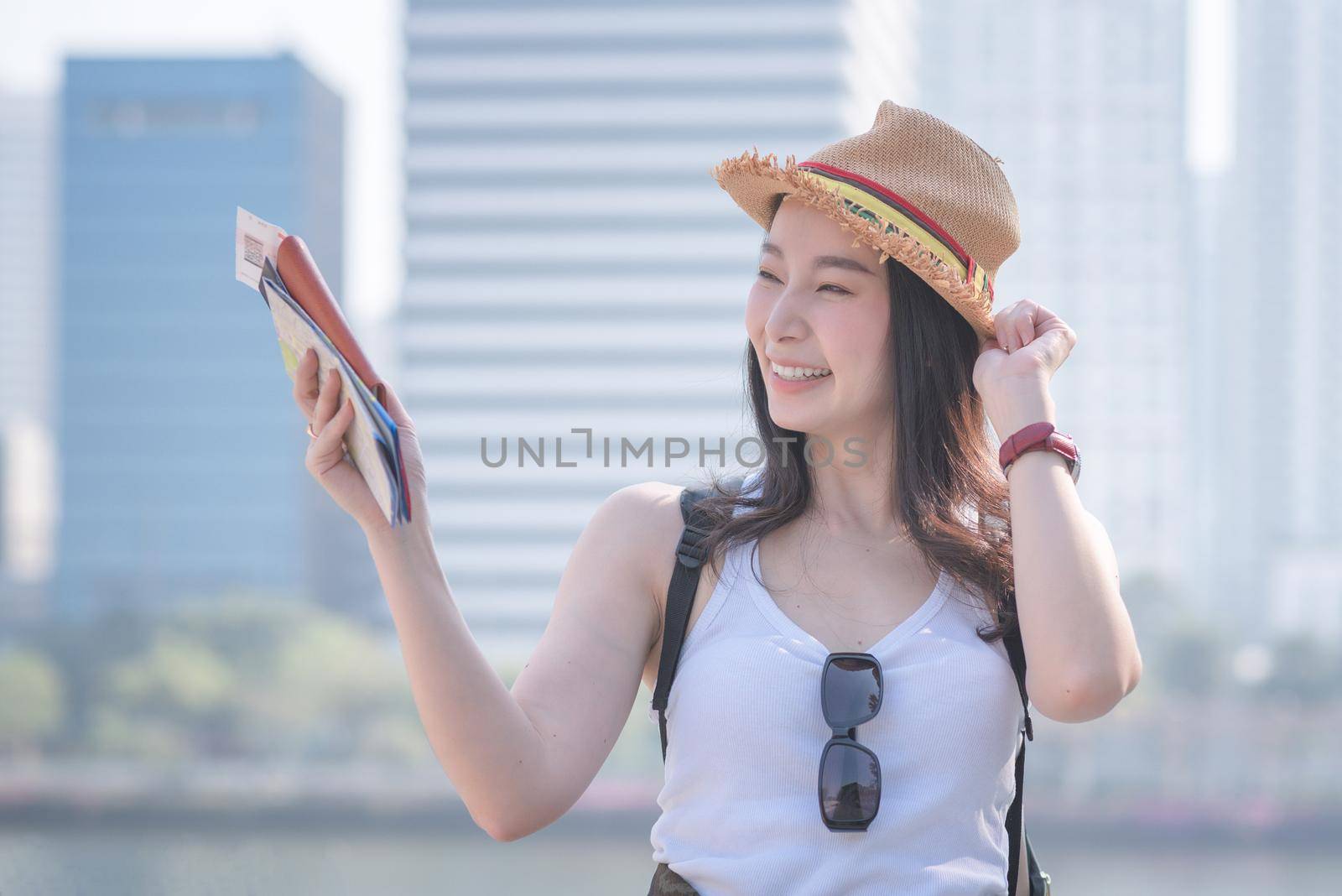 Beautiful asian tourist woman smiling and searching for tourists sightseeing spot. Vacation travel in summer.
