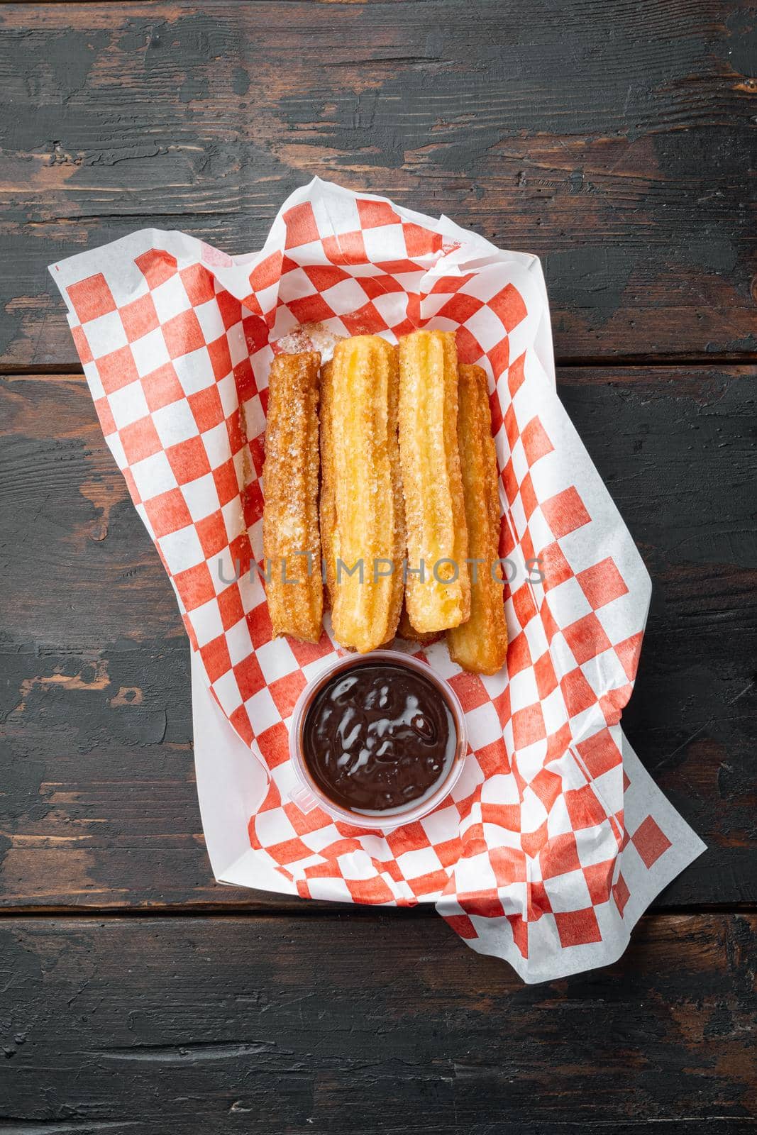 Spanish porras. Spanish food like spanish churros with chocolate, and caramel in paper tray, on old dark wooden table background, top view flat lay