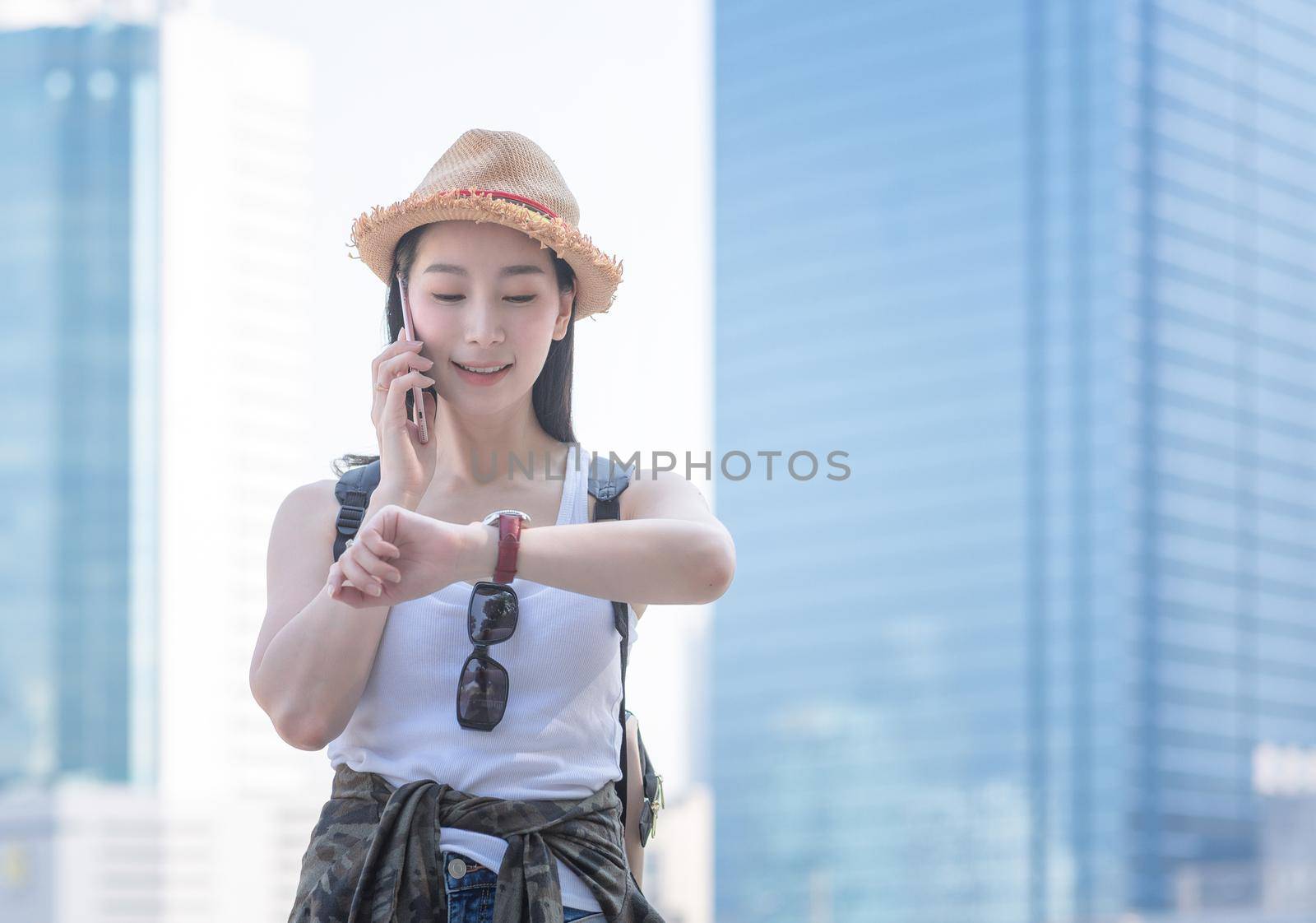 Beautiful asian solo tourist woman smiling and enjoy talking via mobile phone in city downtown. Vacation travel in summer.