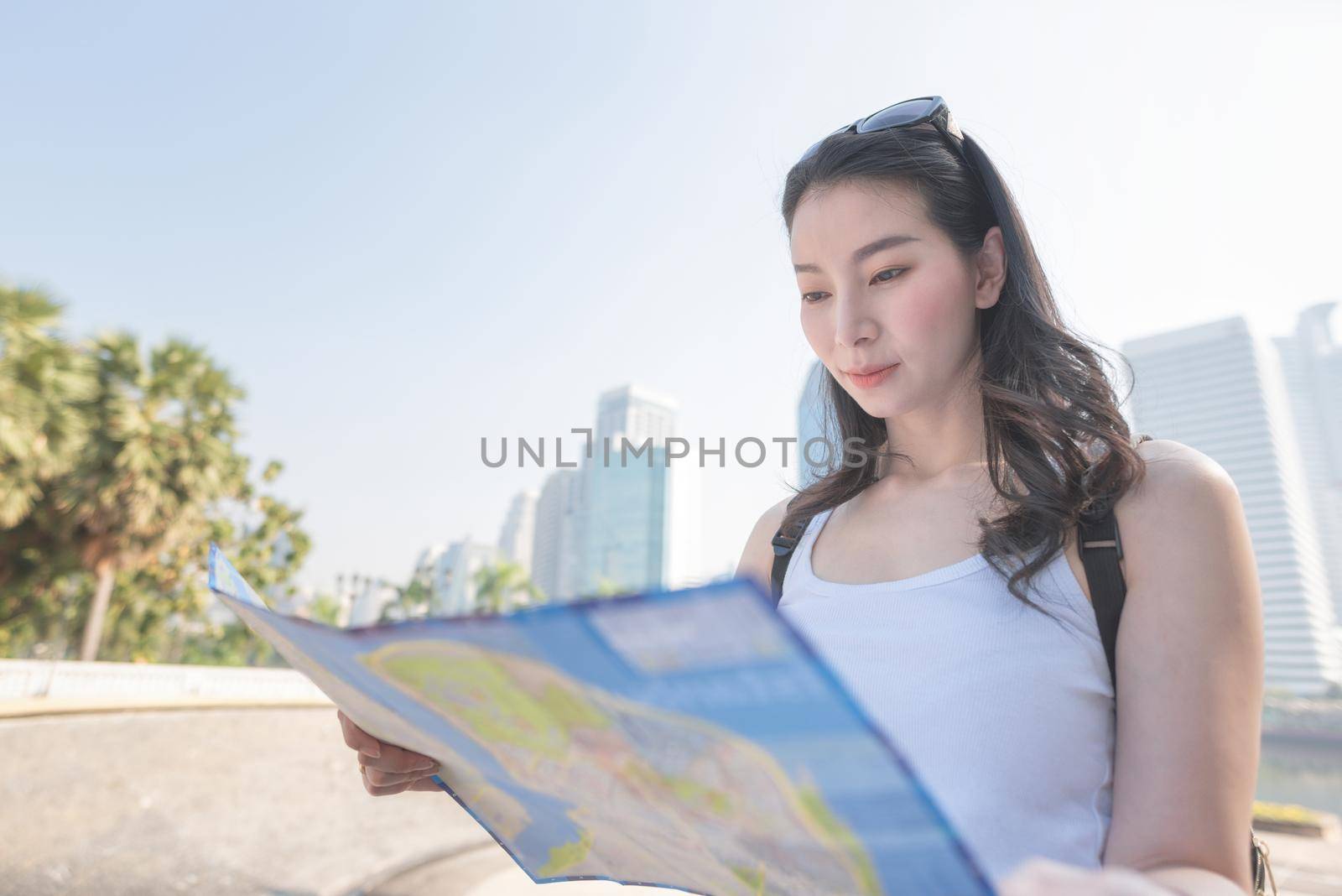 Beautiful asian tourist woman looking at the map searching for tourists sightseeing spot. by Nuamfolio