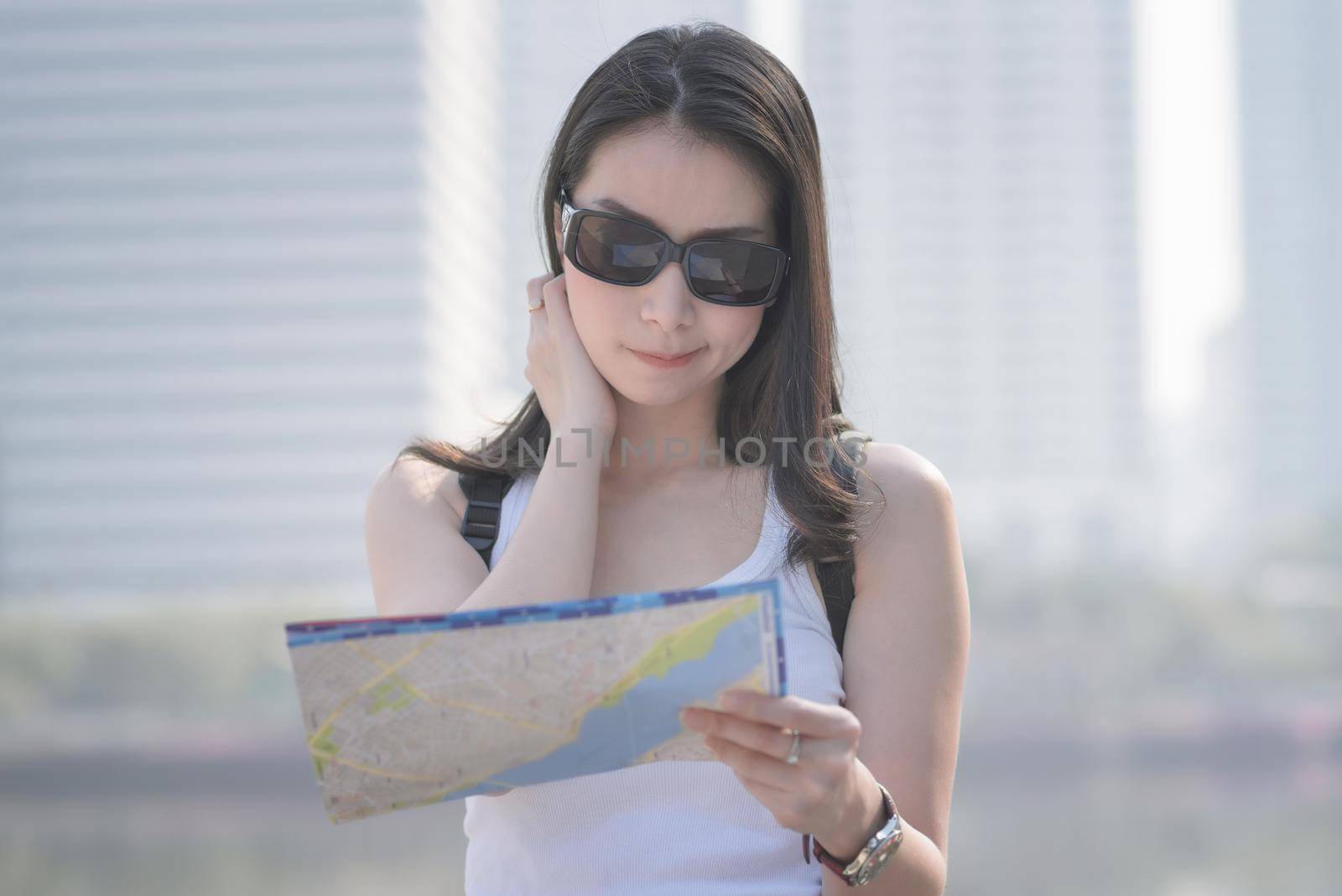 Beautiful asian tourist looking at the map searching for tourists sightseeing spot. Vacation travel in summer.
