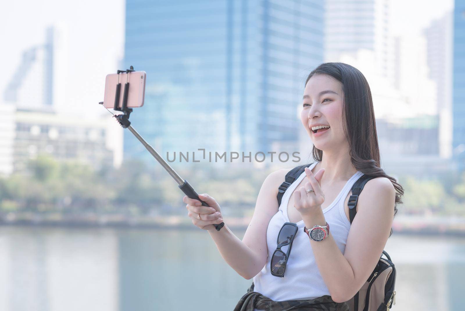 Beautiful asian woman enjoy using video call technology on a smartphone in urban city downtown by Nuamfolio