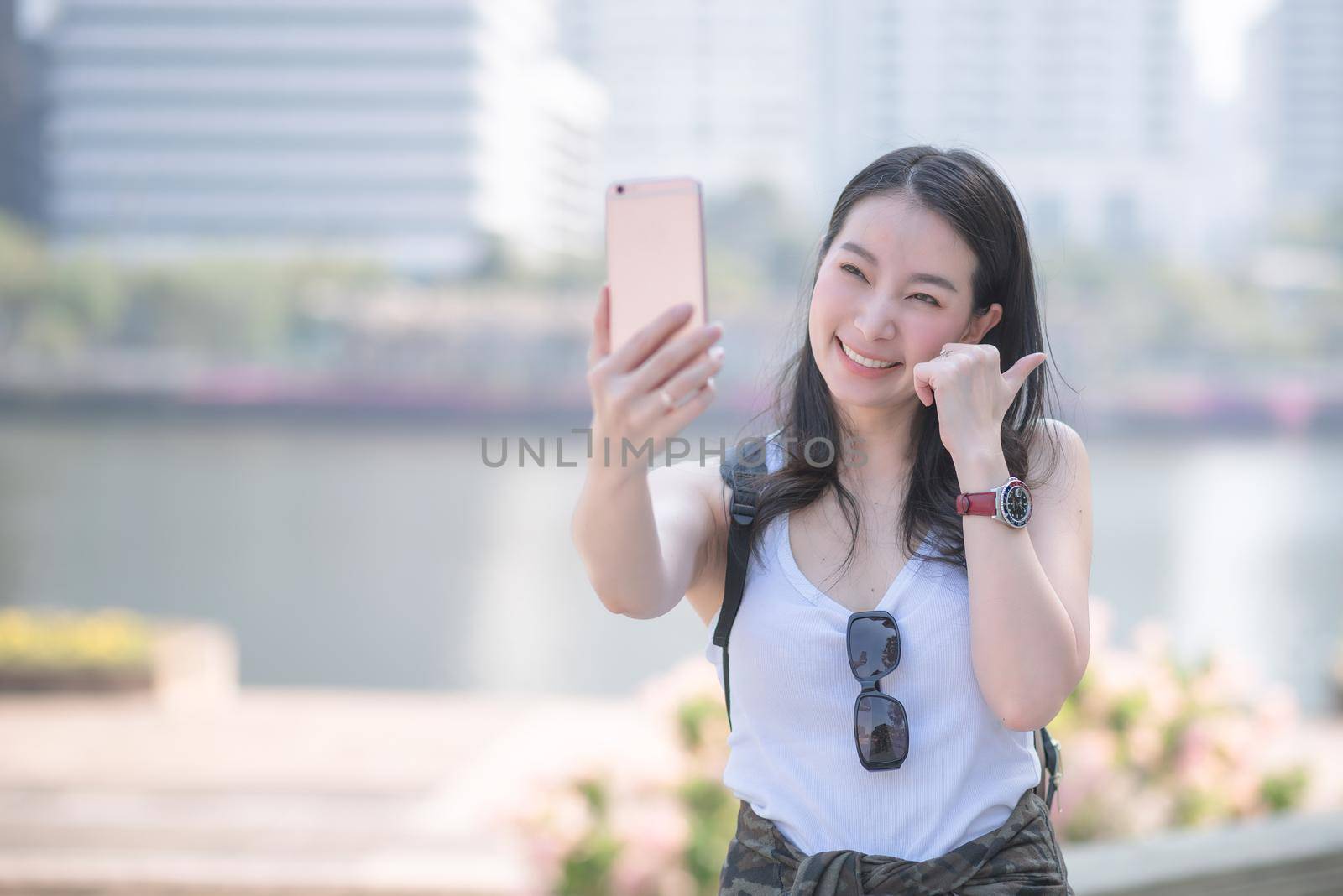 Beautiful asian tourist woman taking selfies on a smartphone in urban city downtown by Nuamfolio