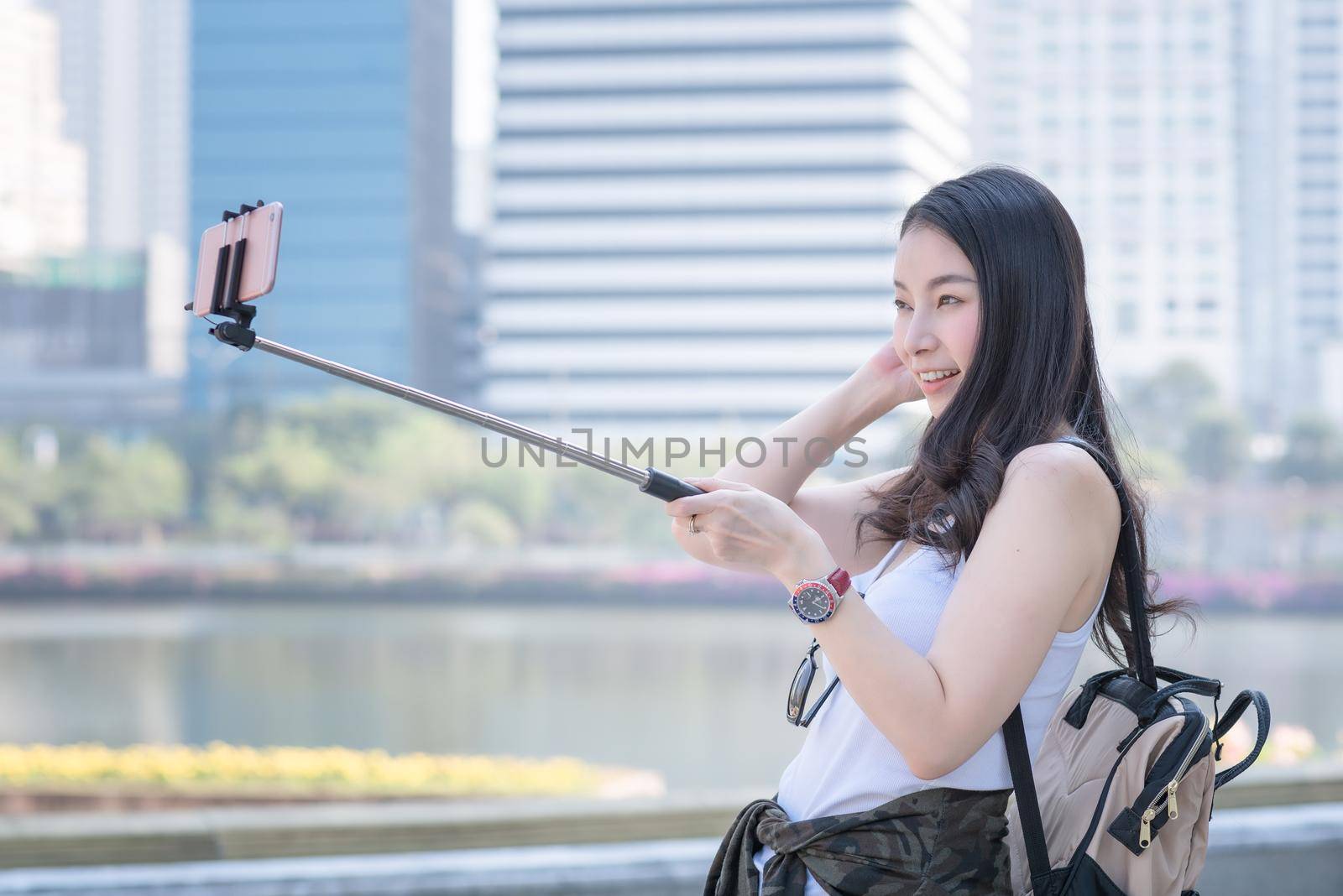 Beautiful asian tourist woman taking selfies on a smartphone in urban city downtown. Vacation travel in summer.