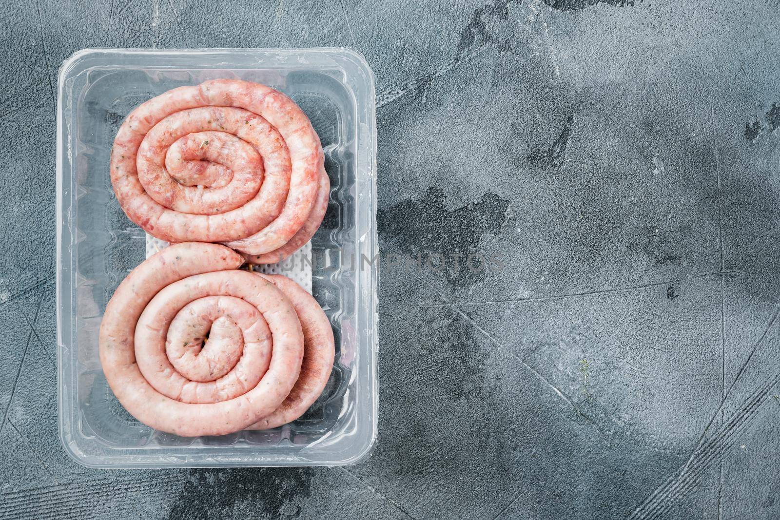 Raw meat sausage set, on gray background, in plastic pack, top view flat lay , with space for text copyspace