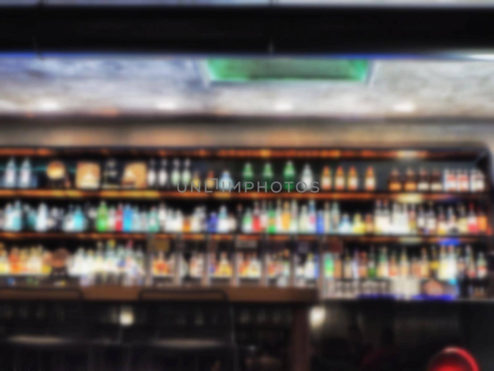 Bar counter and wide liquor bottles shelves defocused bokeh image by lemar