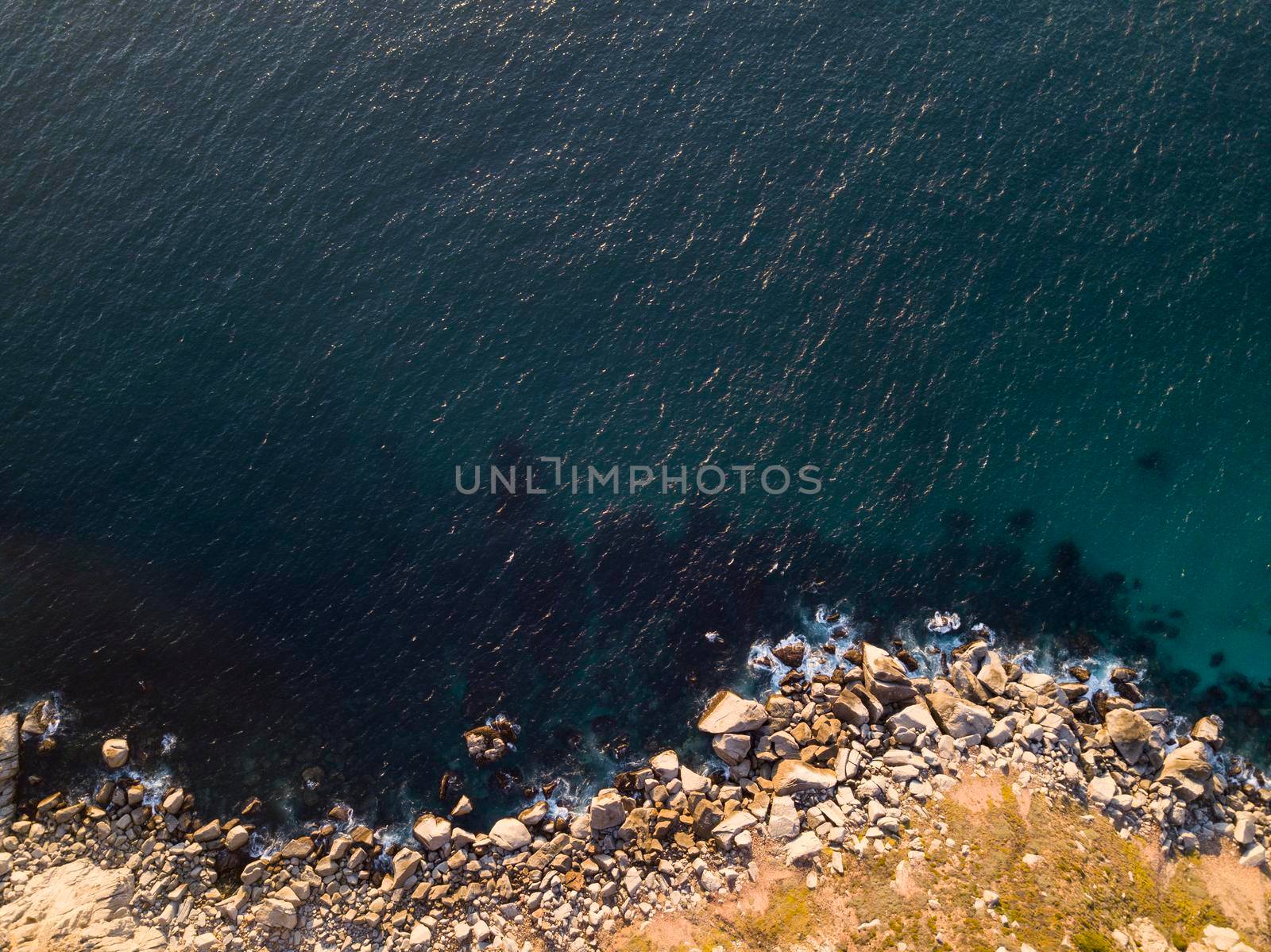 Aerial of rocky coastline and deep clear sea from above by fivepointsix