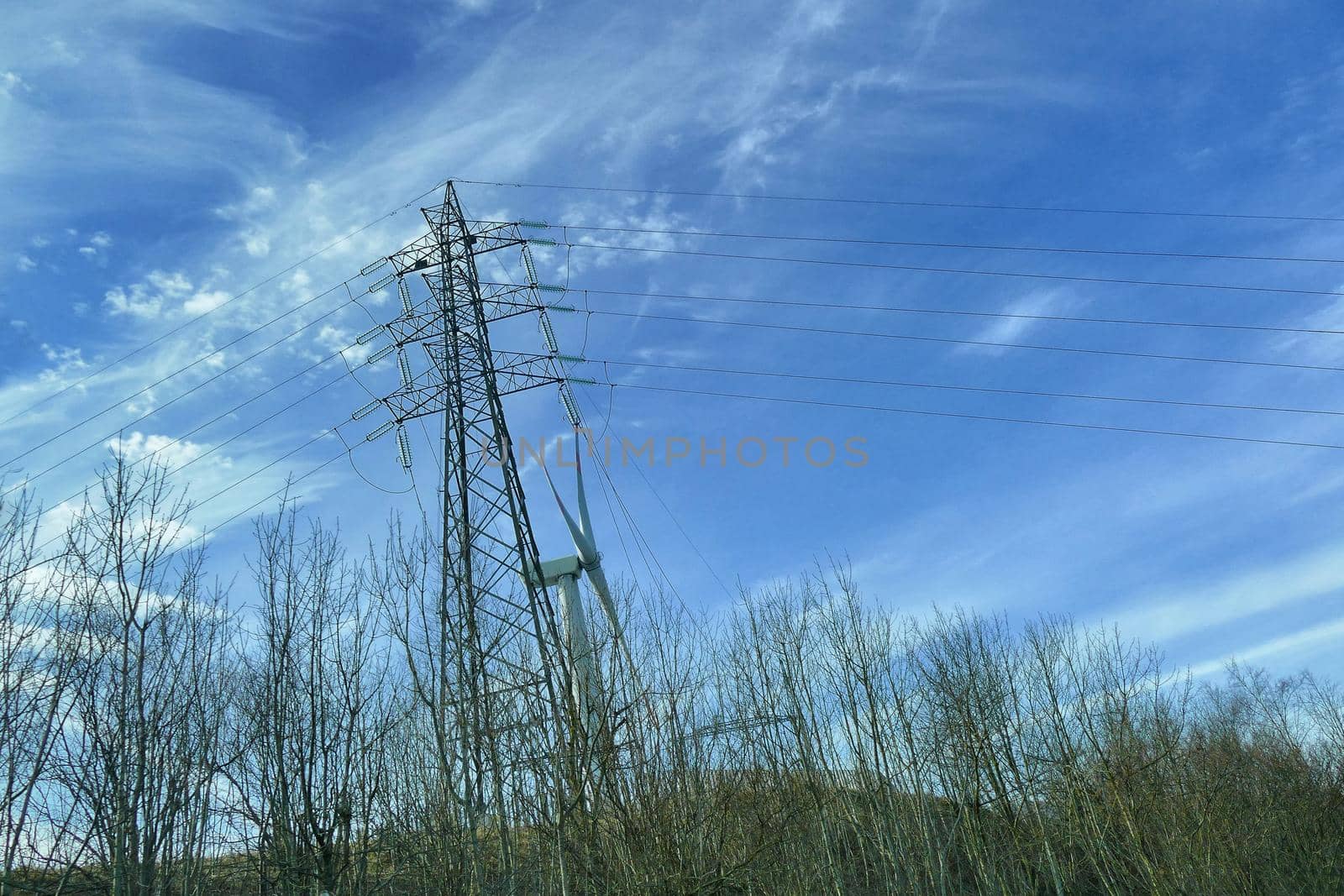 Wind turbine in natural environment near high voltage pylon by lemar