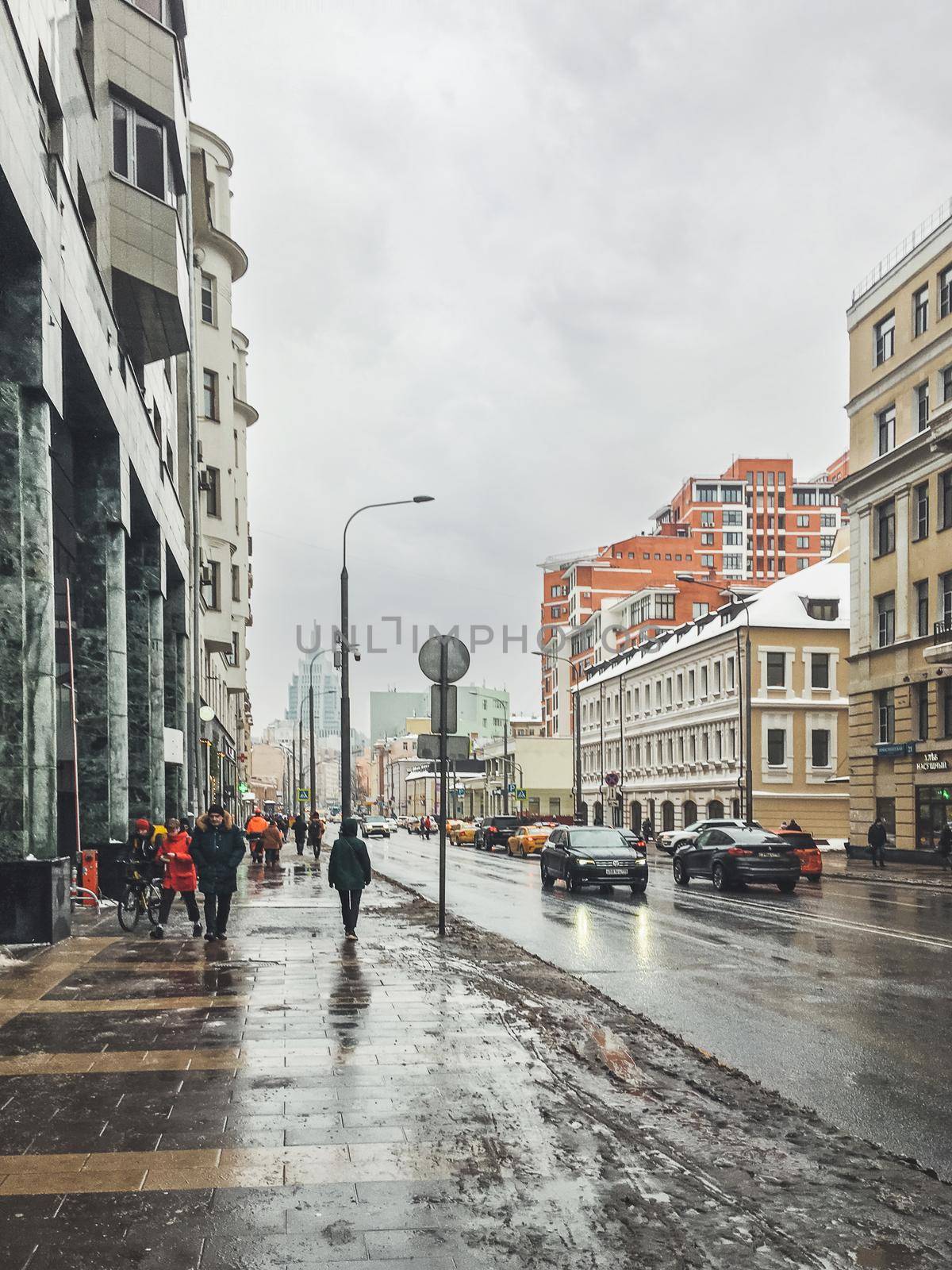 MOSCOW, RUSSIA - January 23, 2021. People and cars on wet streets of Moscow. Snow melted and mixed with mud. by aksenovko