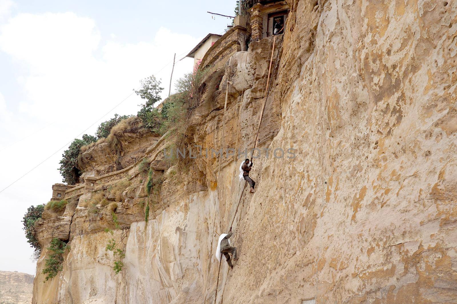 Monks climbing a rock wall at Debre Damo Monastery, Ethiopia