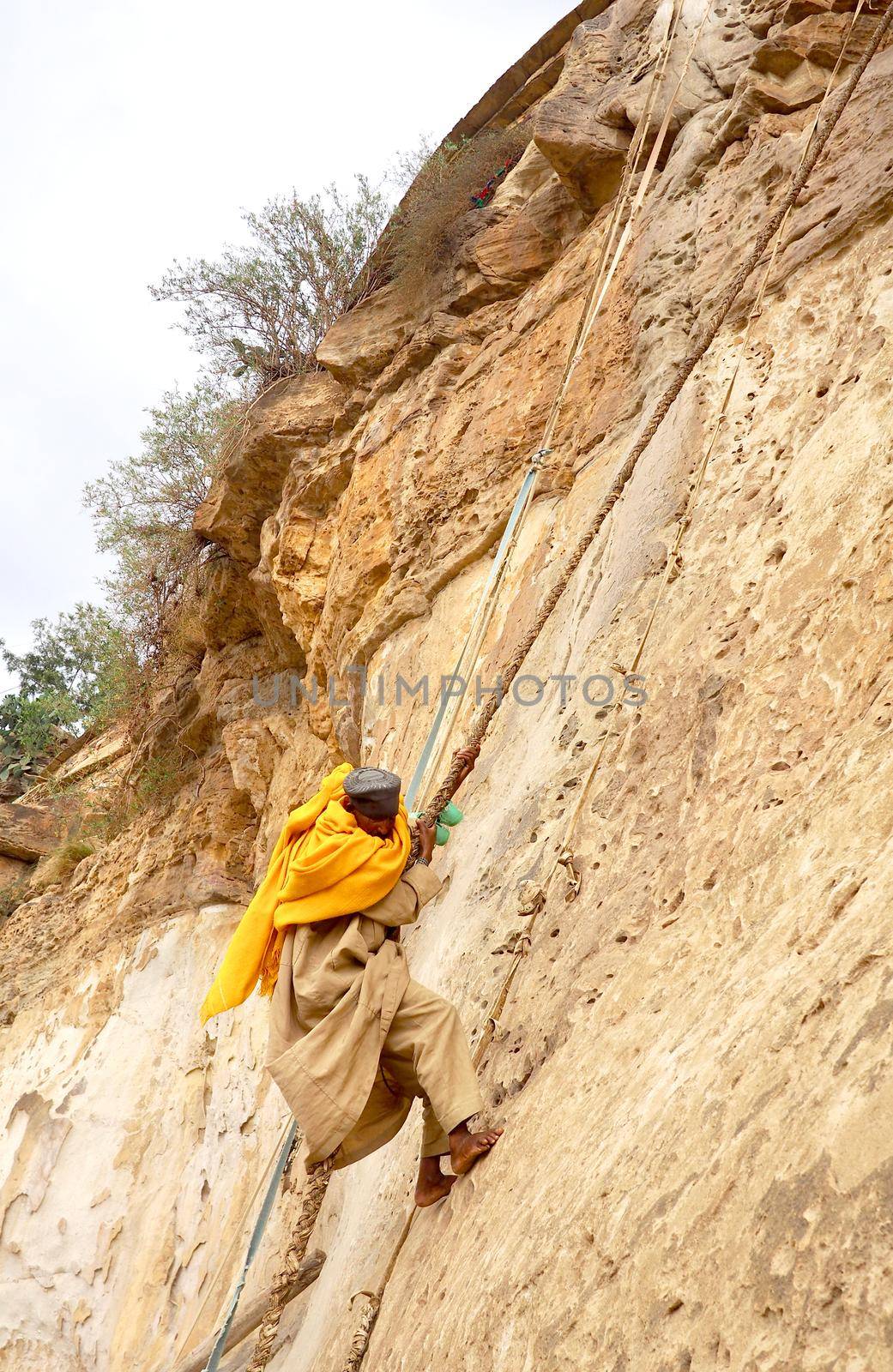 Debre damo, Ethiopia - 7 June 2019 :Monk climbing a rock wall at Debre Damo Monastery, Ethiopia