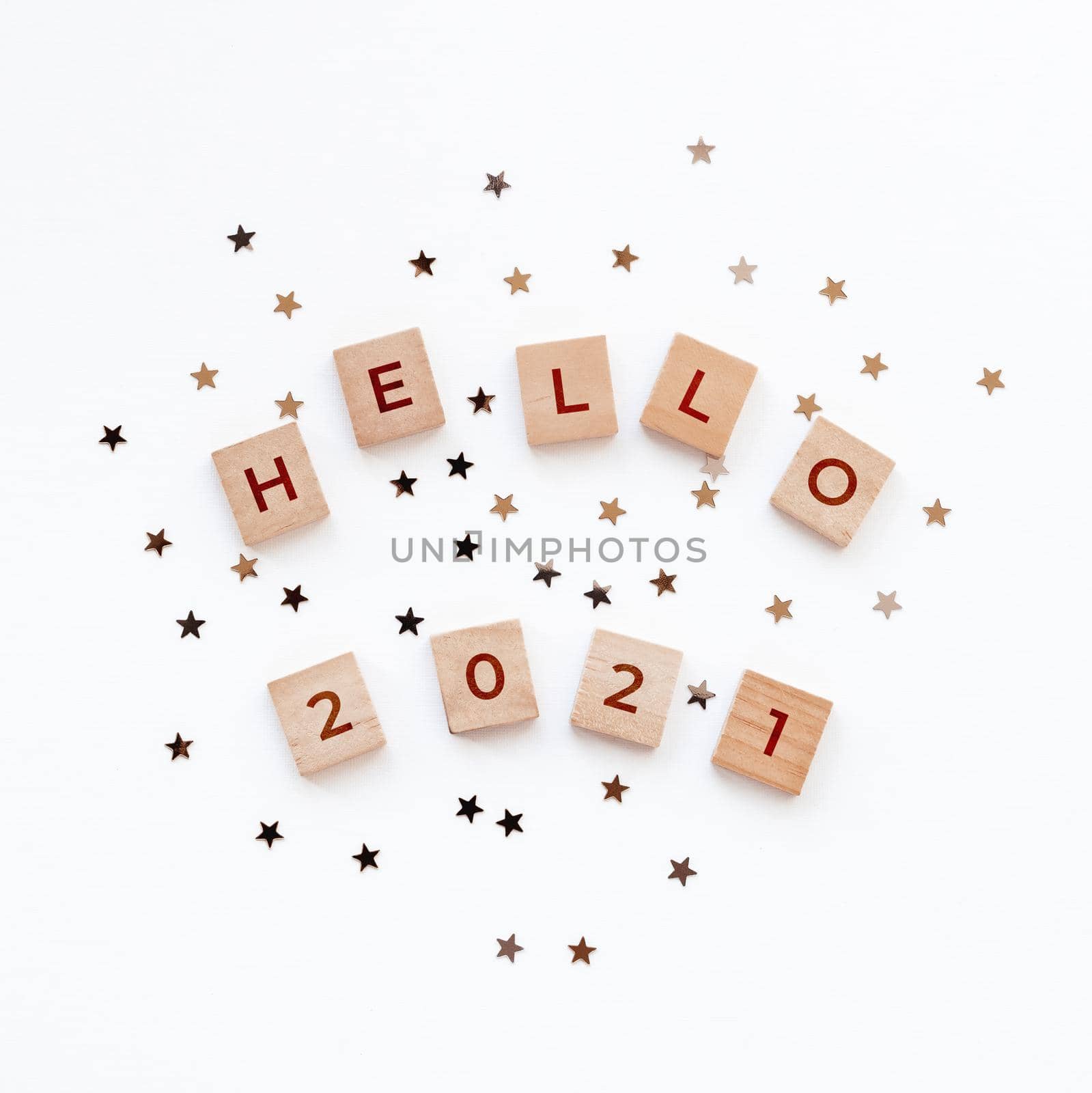 Christmas and New Year background with wooden words HELLO 2021 and star confetti.