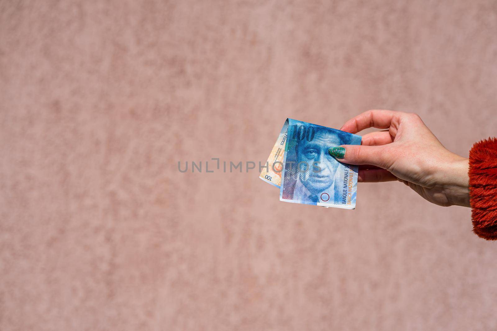 Hand holding showing euro money and giving or receiving money like tips, salary. 100 swiss franc banknotes CHF currency isolated. Concept of rich business people, saving or spending money.