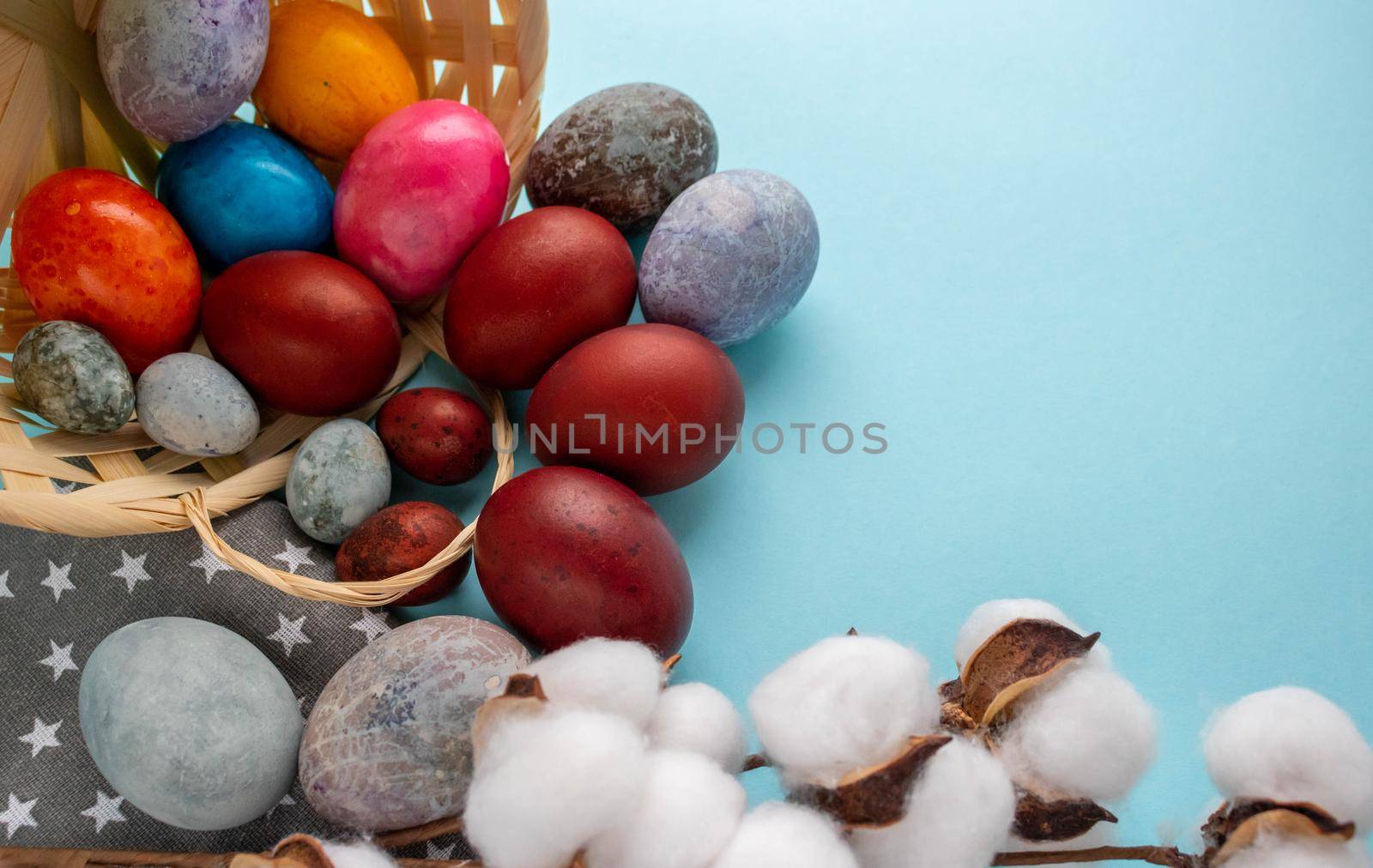 Colorful eggs spilled out of the basket onto the blue background. The concept of Easter. Space for text by lapushka62