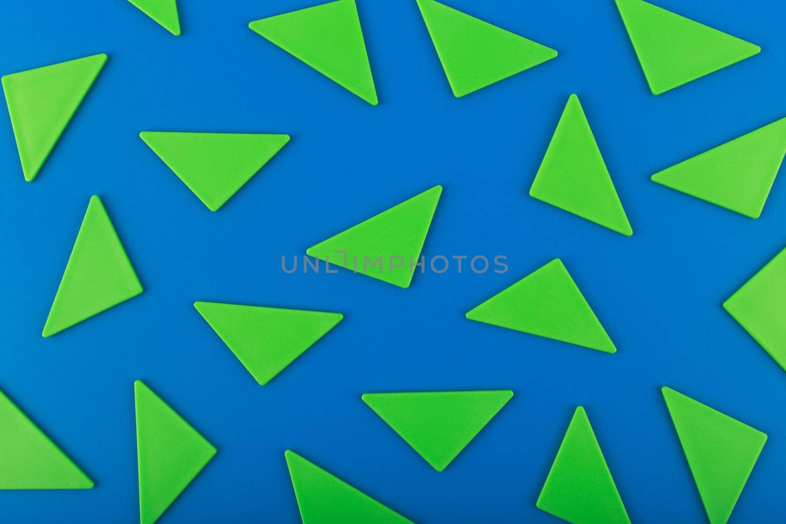 Flat lay with bright green plastic triangles against blue background