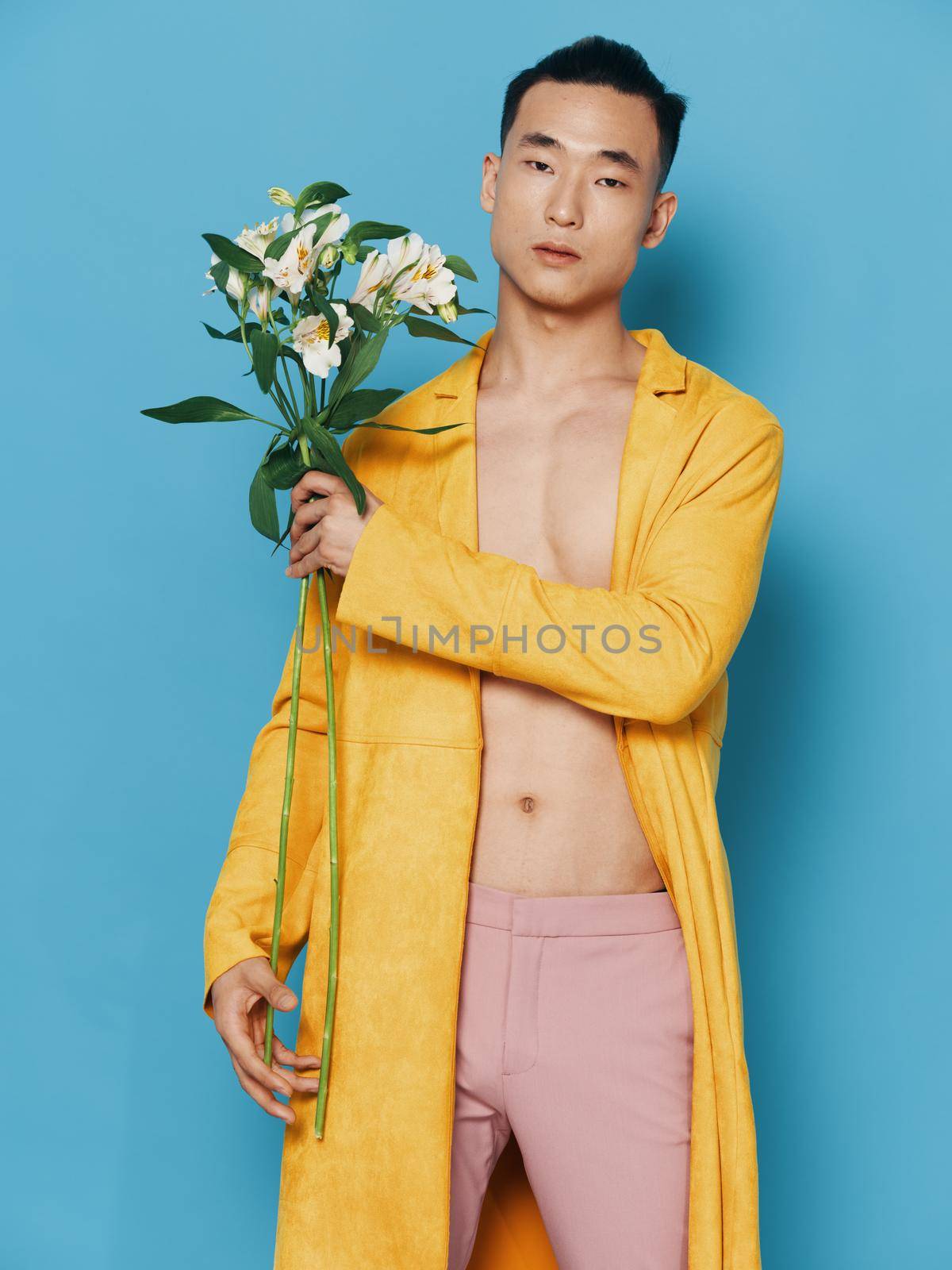 Sexy man with a bouquet of white flowers and an unbuttoned pink pants model. High quality photo