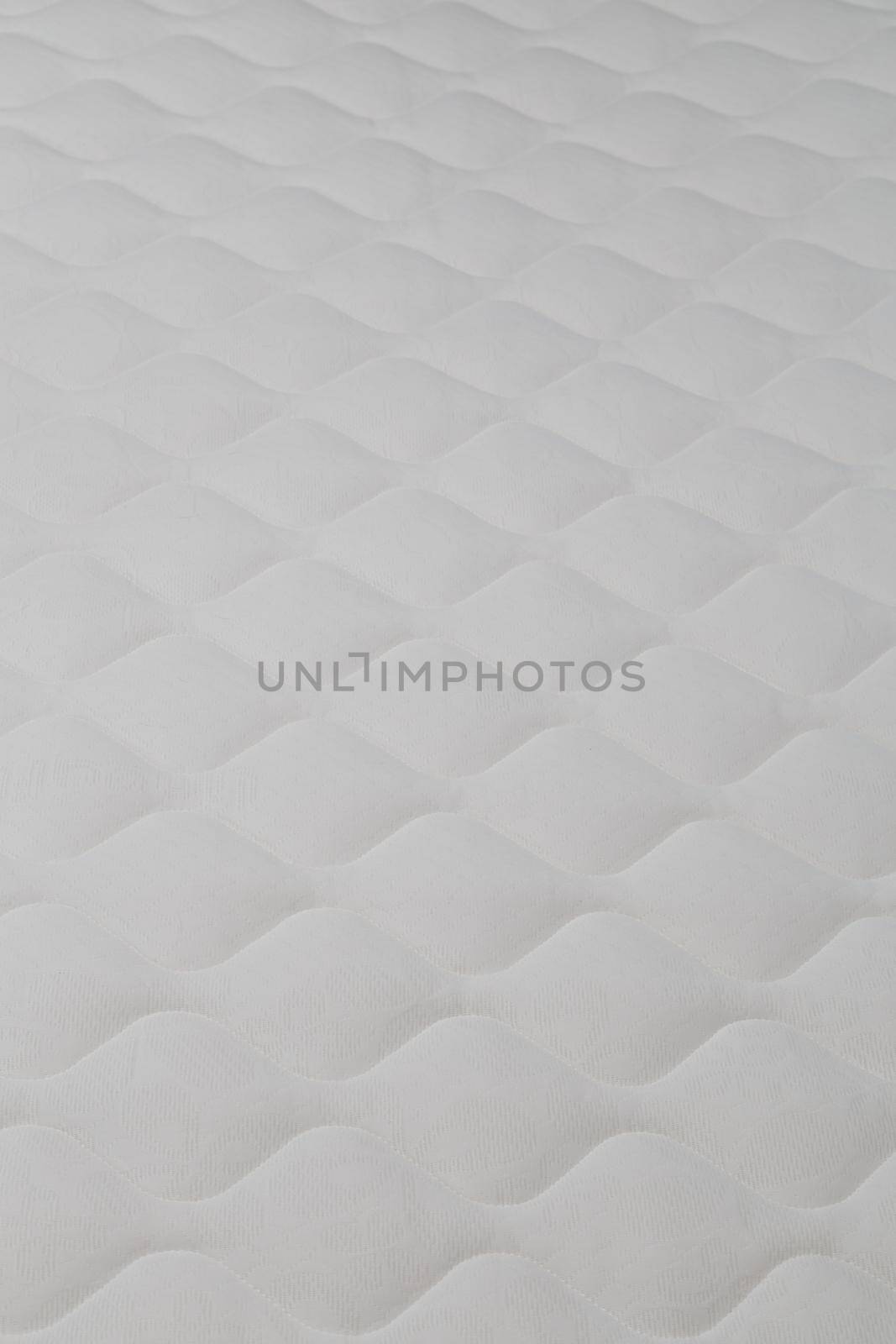 Soft white mattress close-up background with selective focus and blur.