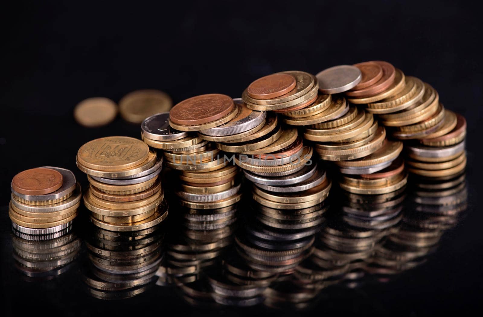 Stacks cf different country coins on black background.