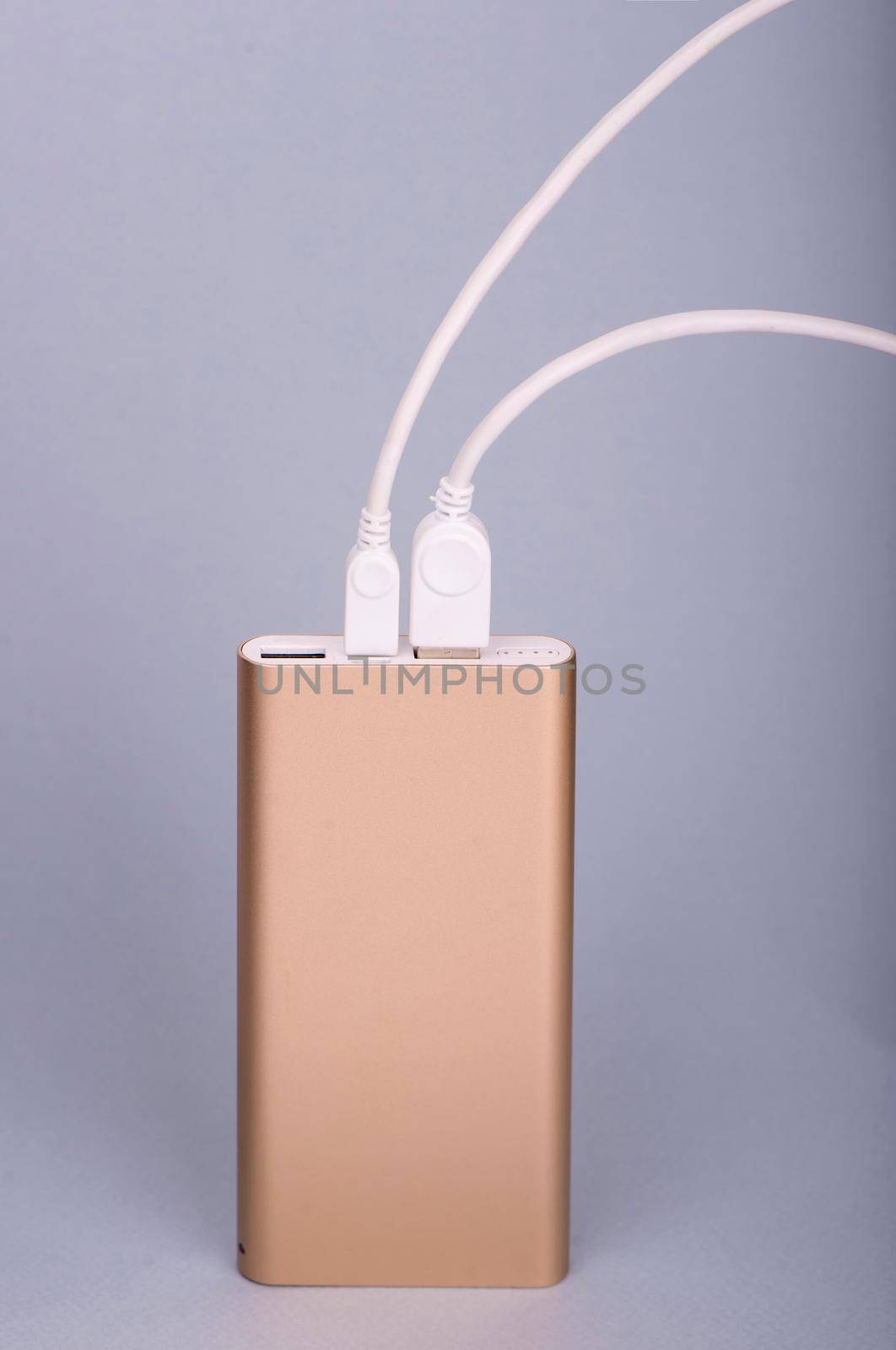 Smartphone charging with power bank on a blue background.