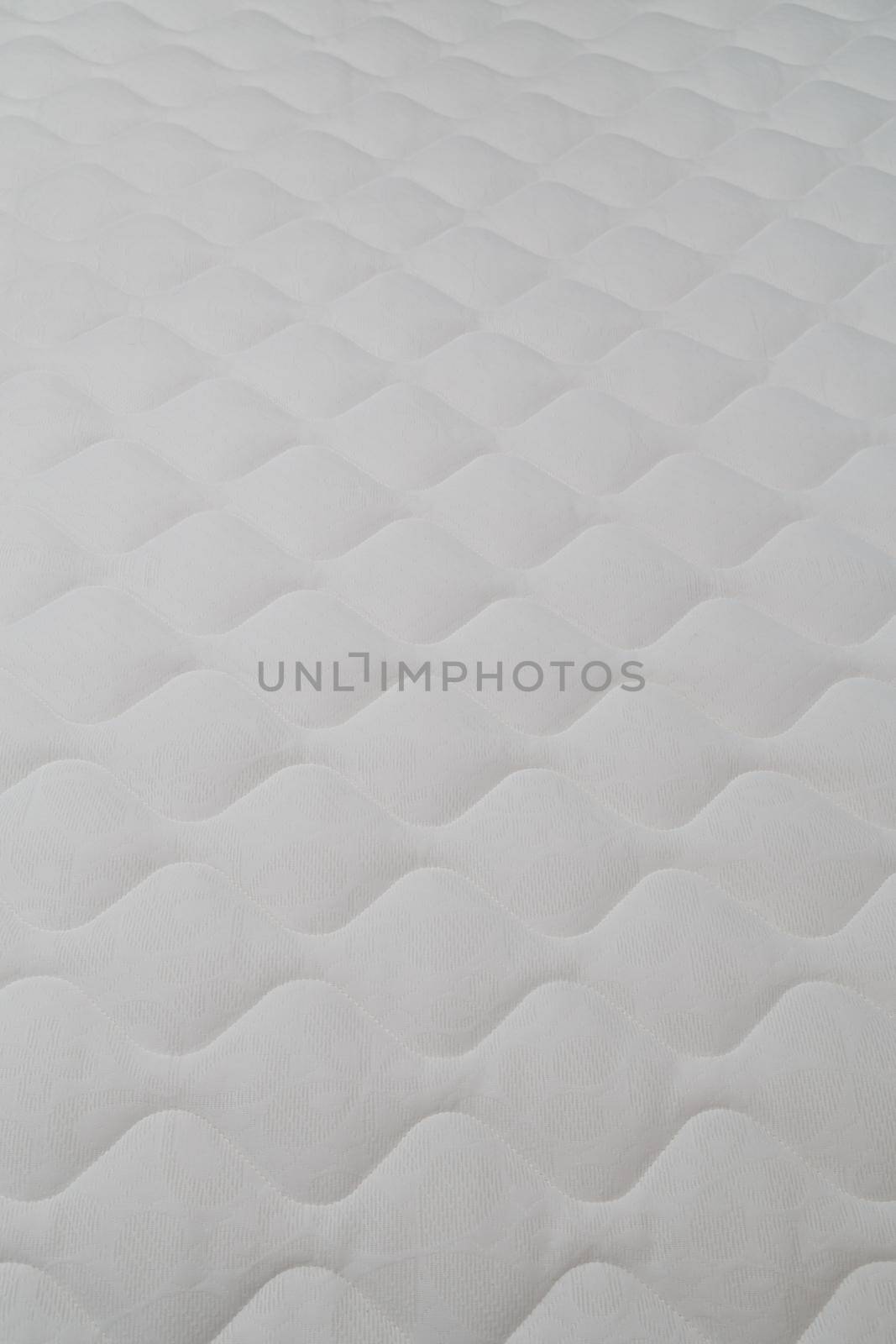 Soft white mattress close-up background with selective focus and blur.