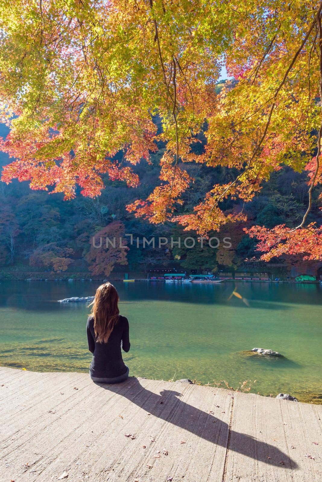 Tourist sitting and relaxing with beautiful nature view of Arashiyama in autumn season in Kyoto, Japan. Arashiyama is a one of attraction landmark for tourist in Kyoto, Japan by Nuamfolio