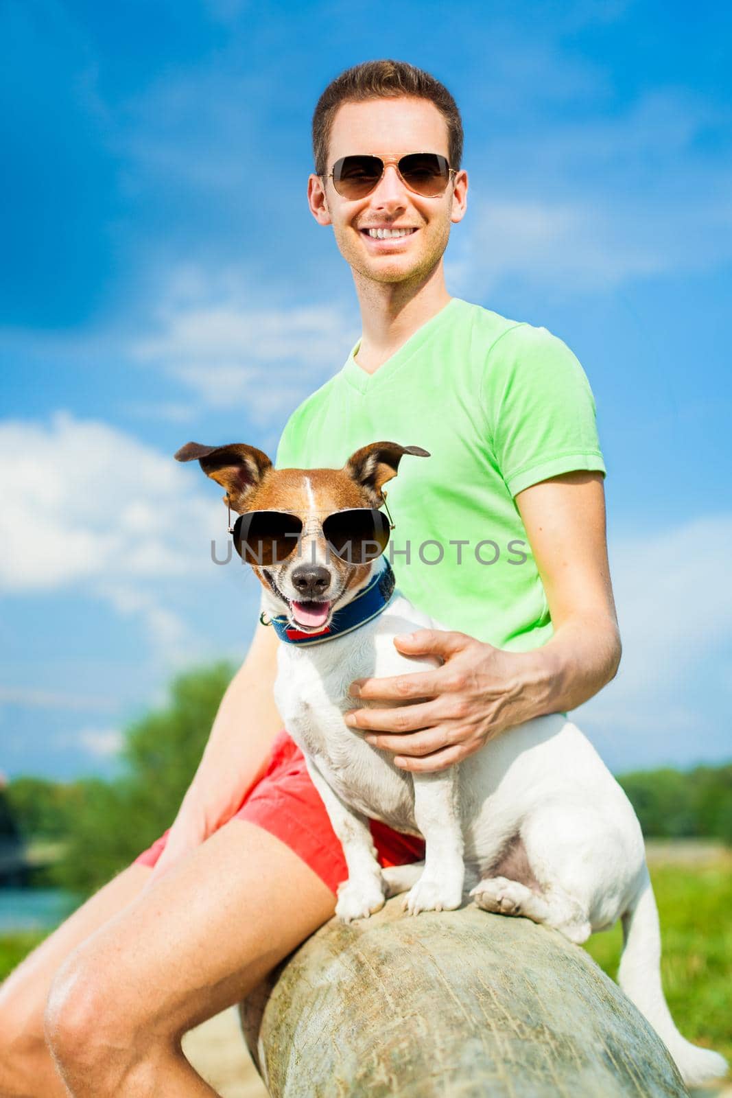 dog and owner observing together , sitting very close together having a good time outdoors in the park