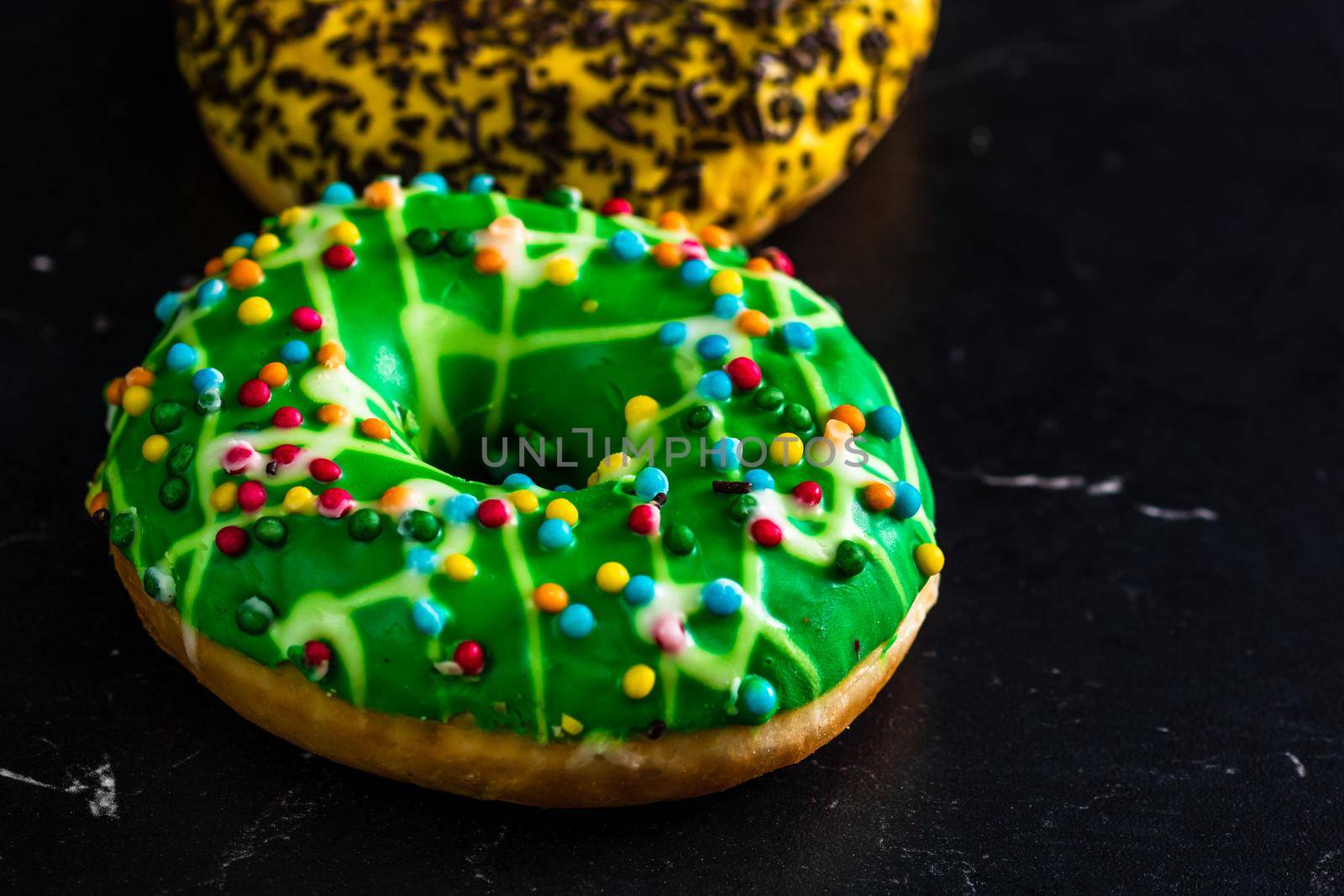 Green glazed donut with sprinkles isolated. Close up of colorful donut. by vladispas