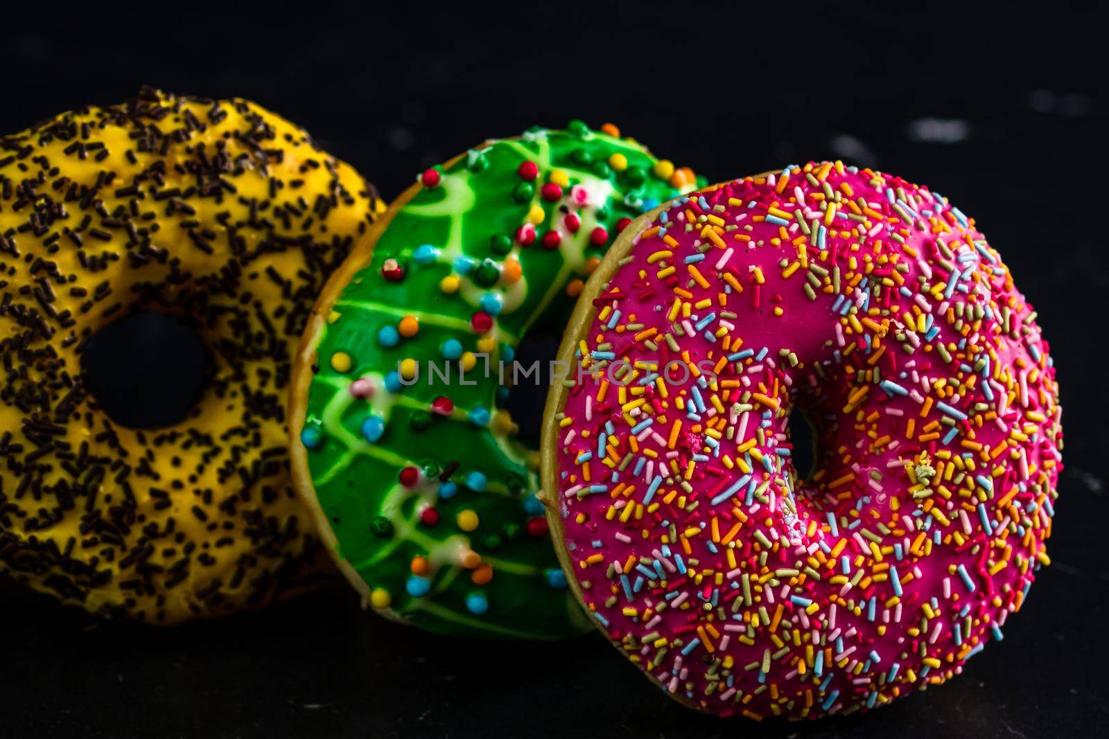 Glazed donuts with sprinkles isolated. Close up of colorful donuts.