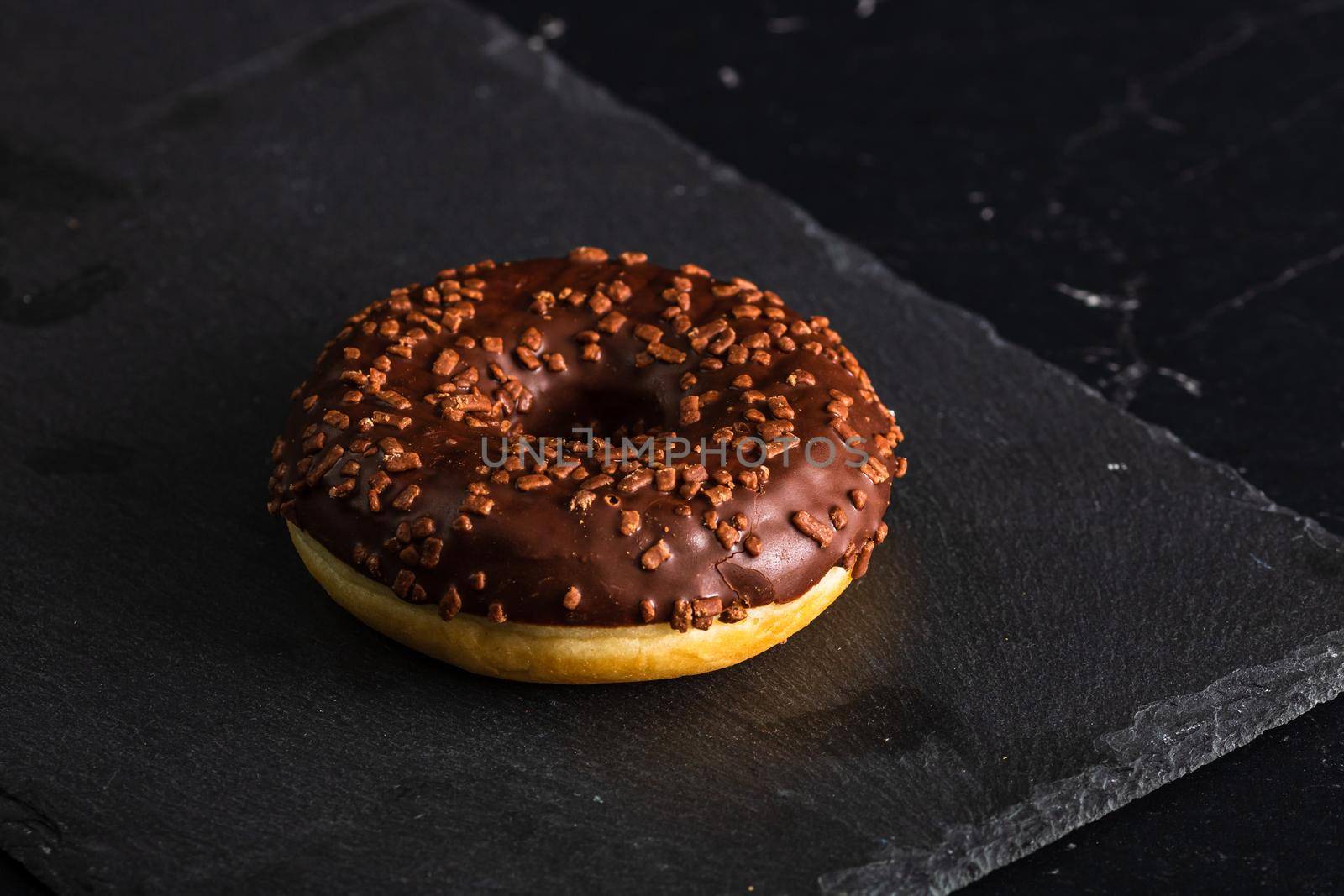 Chocolate glazed donut with chocolate chips isolated. Close up of delicious donut. by vladispas