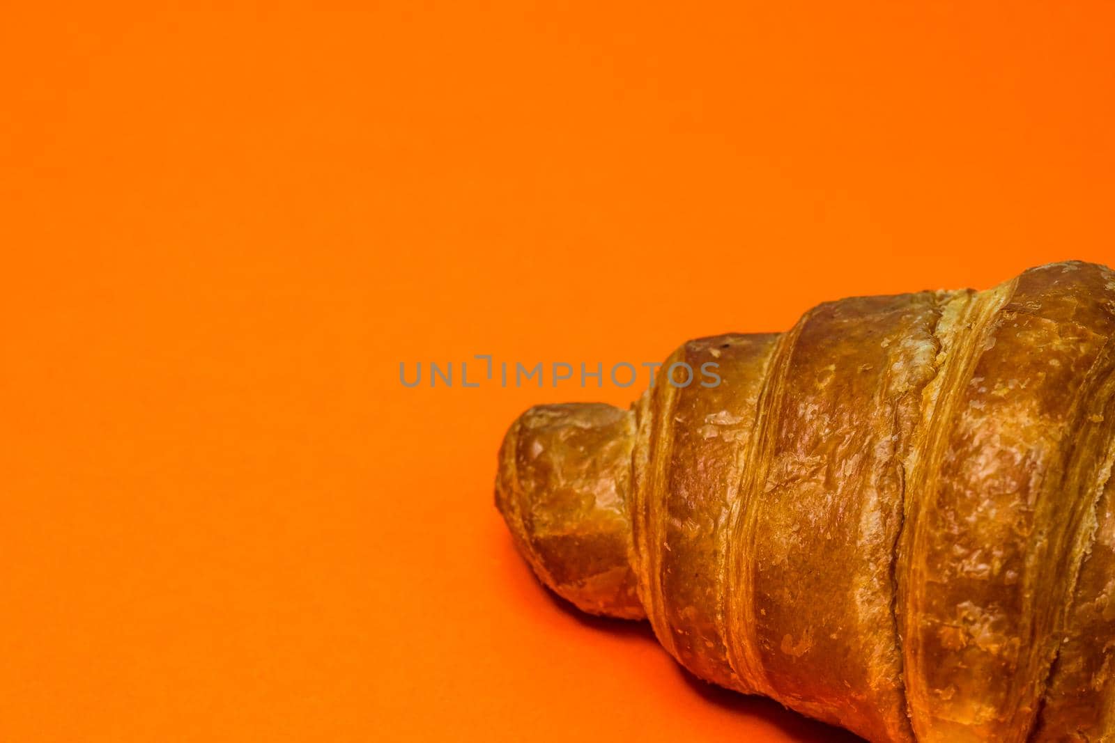 Fresh croissant isolated on orange board. French breakfast concept.